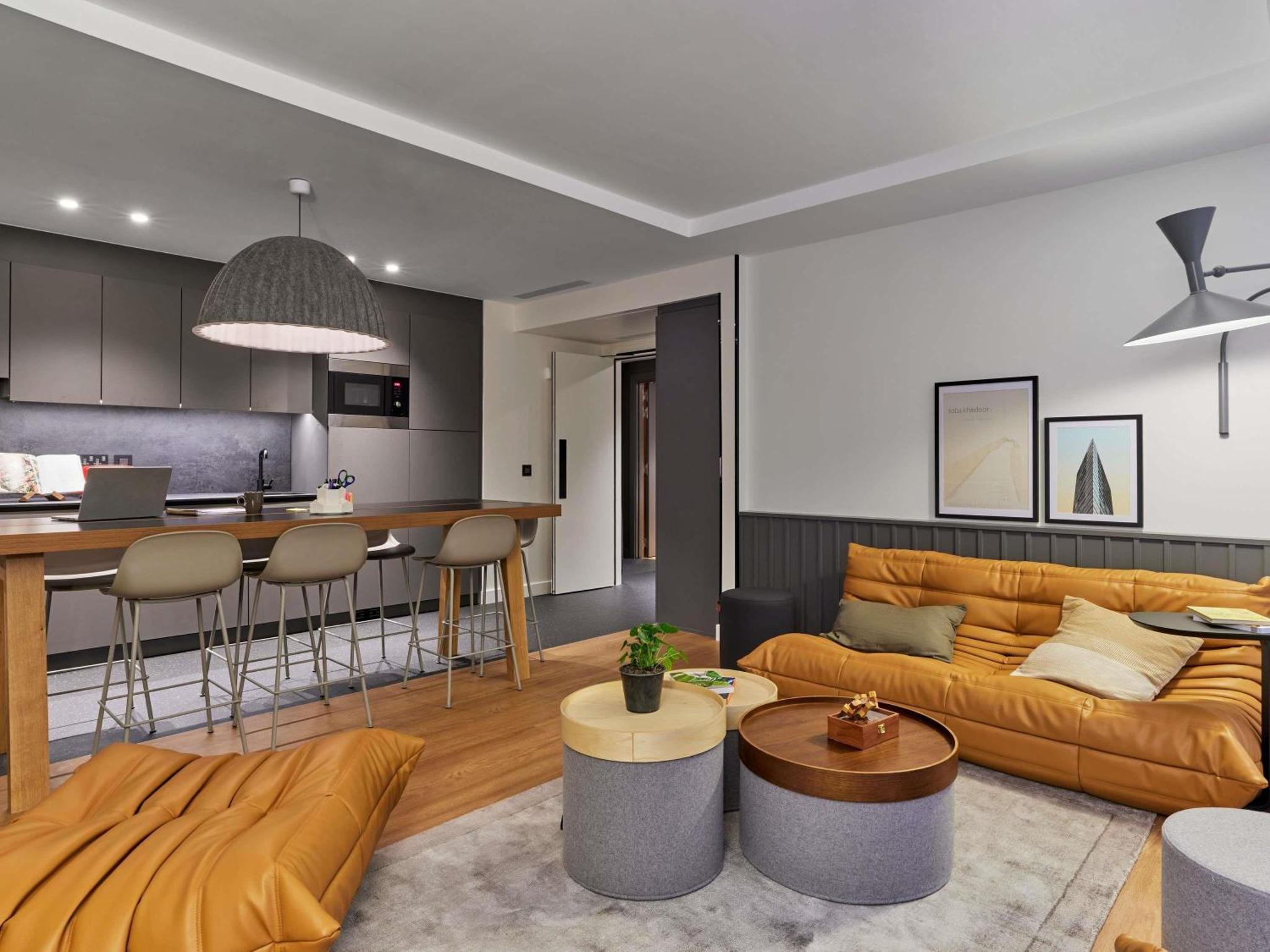 a living room with a couch and a kitchen at Aparthotel Adagio London City East in London +62 photos