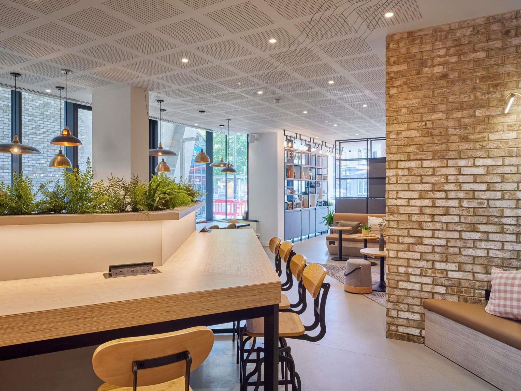 a restaurant with a bar with chairs and a brick wall at Aparthotel Adagio London City East in London