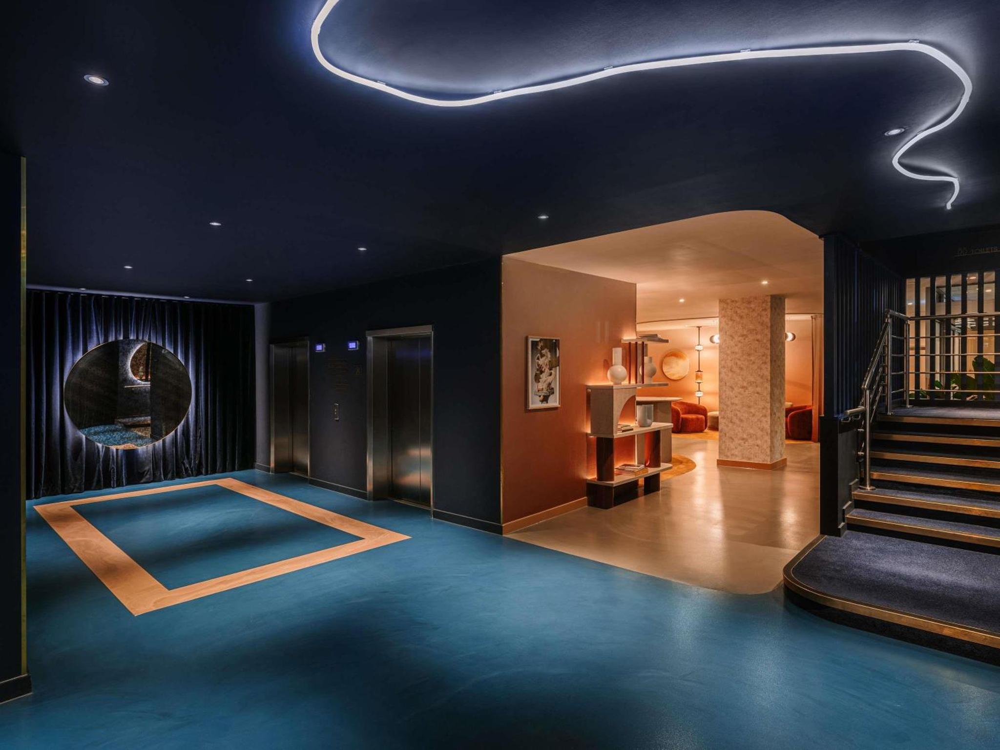 a living room with a blue floor and a staircase at Mercure London Earls Court in London