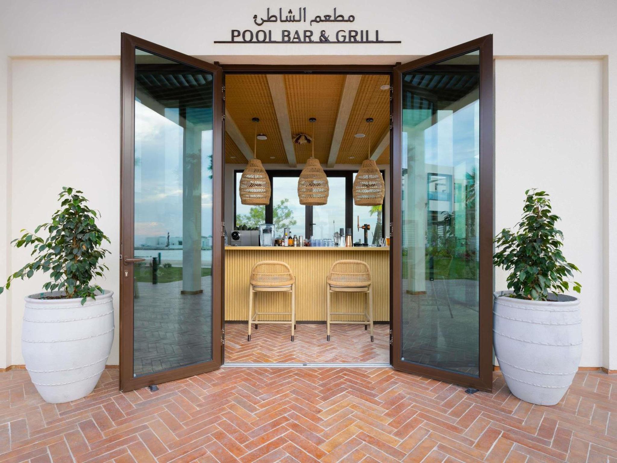 a restaurant with two potted plants and a bar and grill at Hawar Resort By Mantis in Hawar Island +196 photos