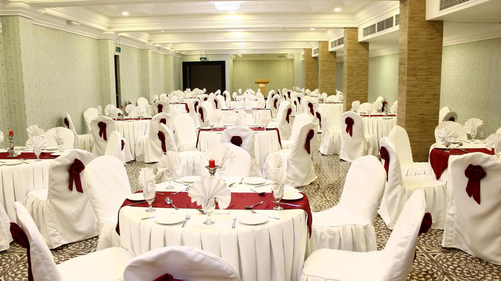 a banquet hall with white tables and white chairs at Bahrain International Hotel in Manama +55 photos