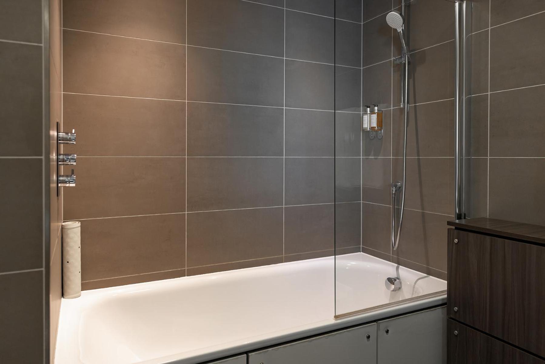 a bathroom with a bath tub with a shower at Hotel Xanadu in London