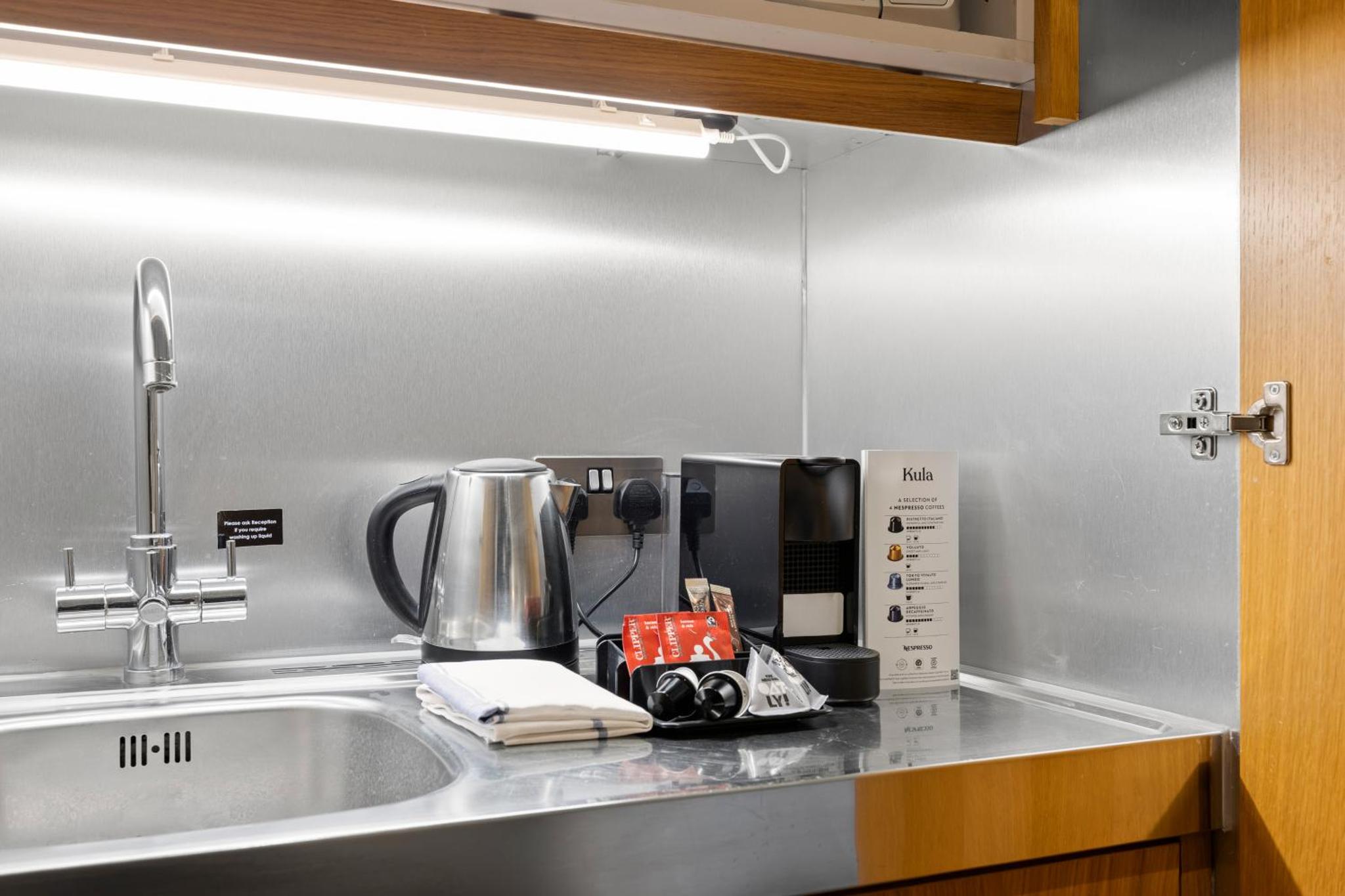 a kitchen counter with a sink with a coffee maker at Stay Kula London - Kensington in London