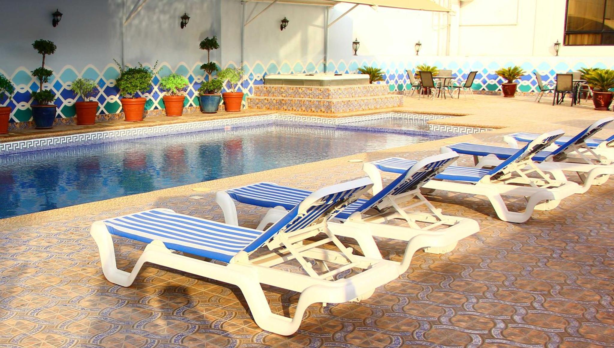 a row of lounge chairs next to a swimming pool at Bahrain International Hotel in Manama