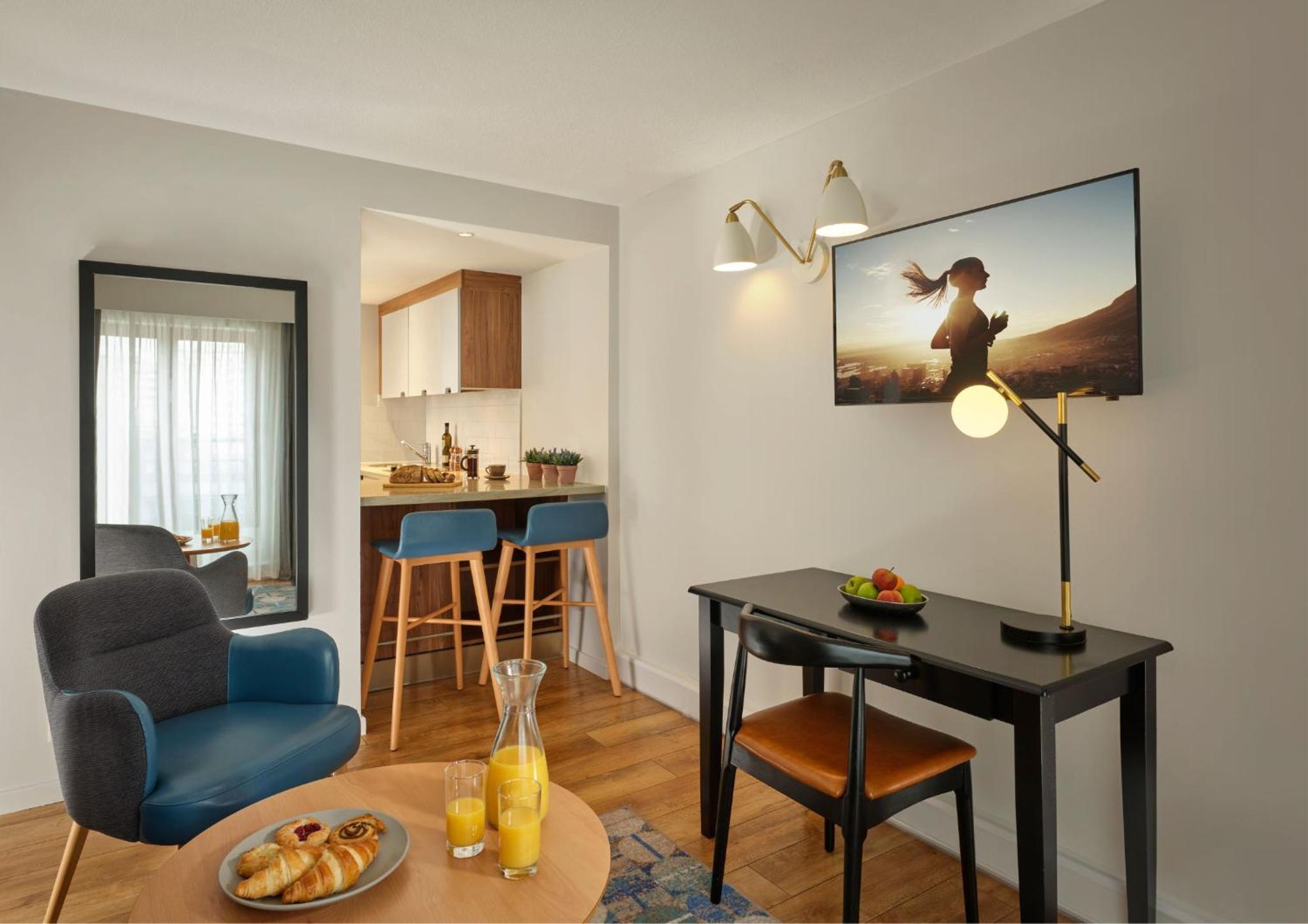 a living room with a table and a room with a kitchen at Citadines Barbican London in London