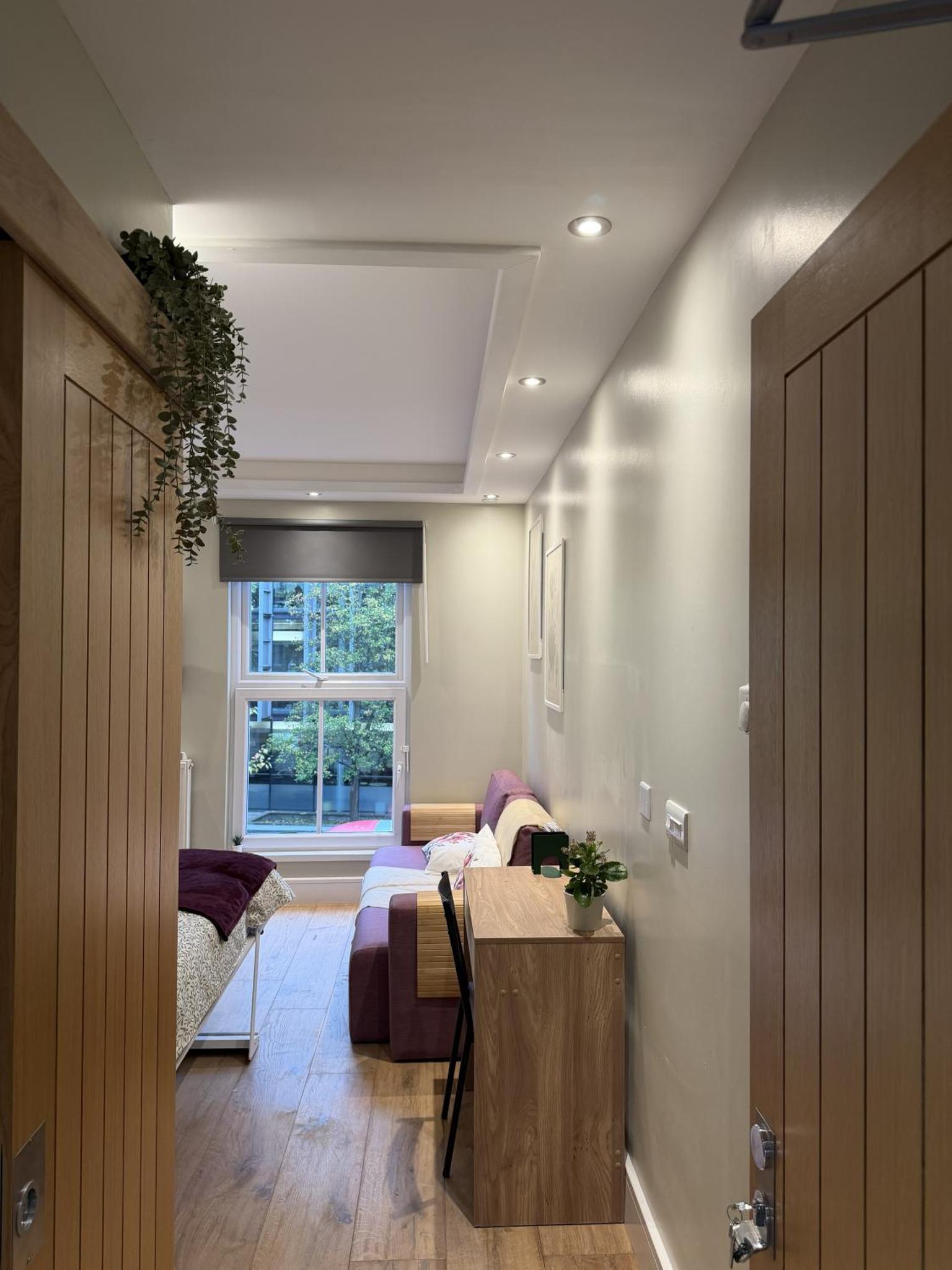 a bedroom with a bed and a table and a window at KAStay london in London