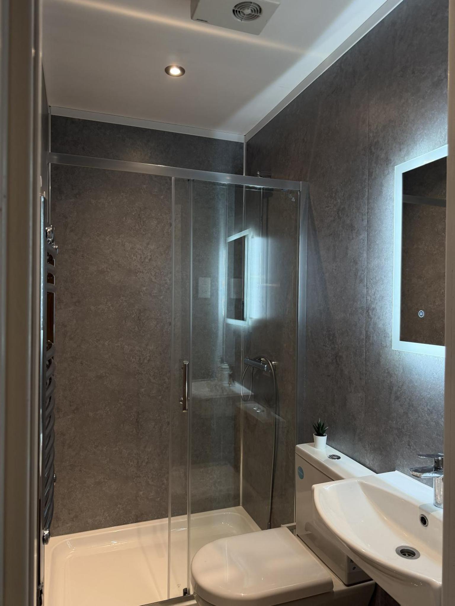 a bathroom with a shower and a toilet and a sink at KAStay london in London