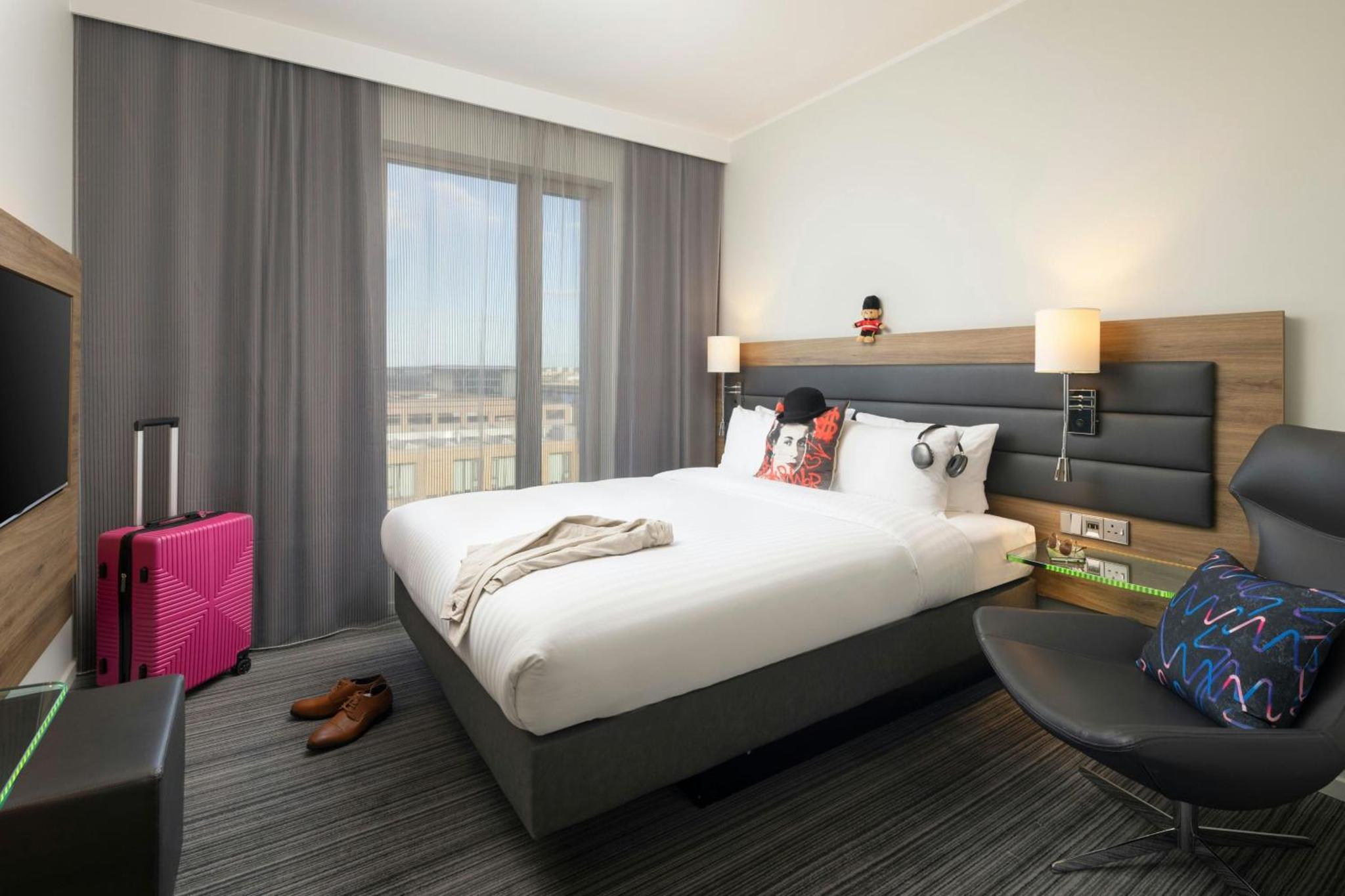 a hotel room with a bed and a chair at Moxy London Excel in London