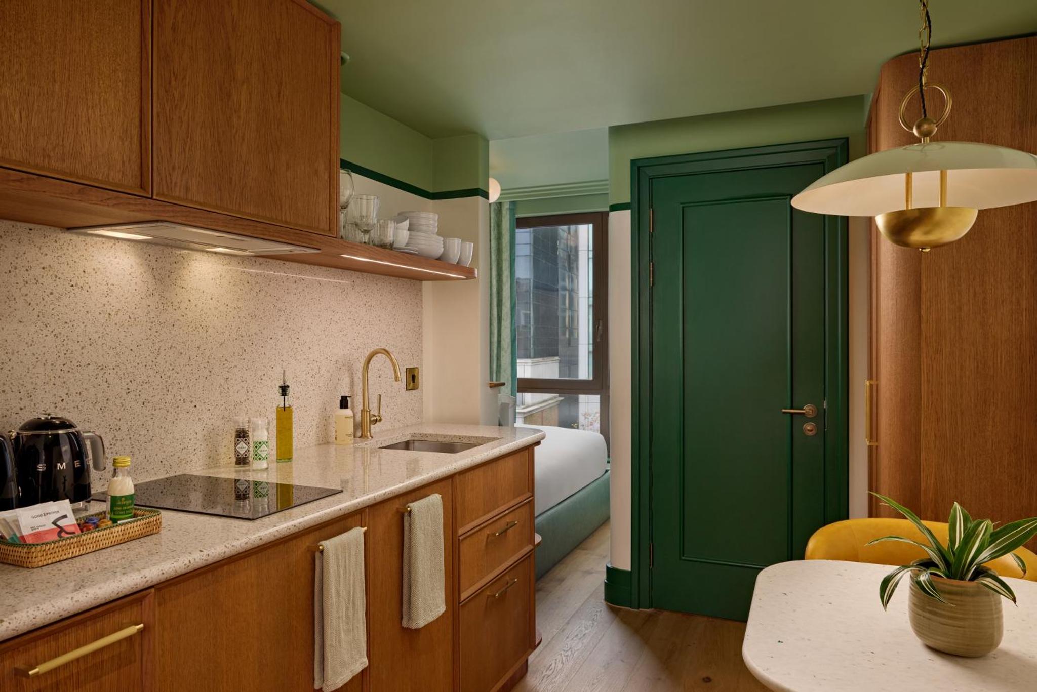 a kitchen with green walls and a green door at The July - London Victoria in London