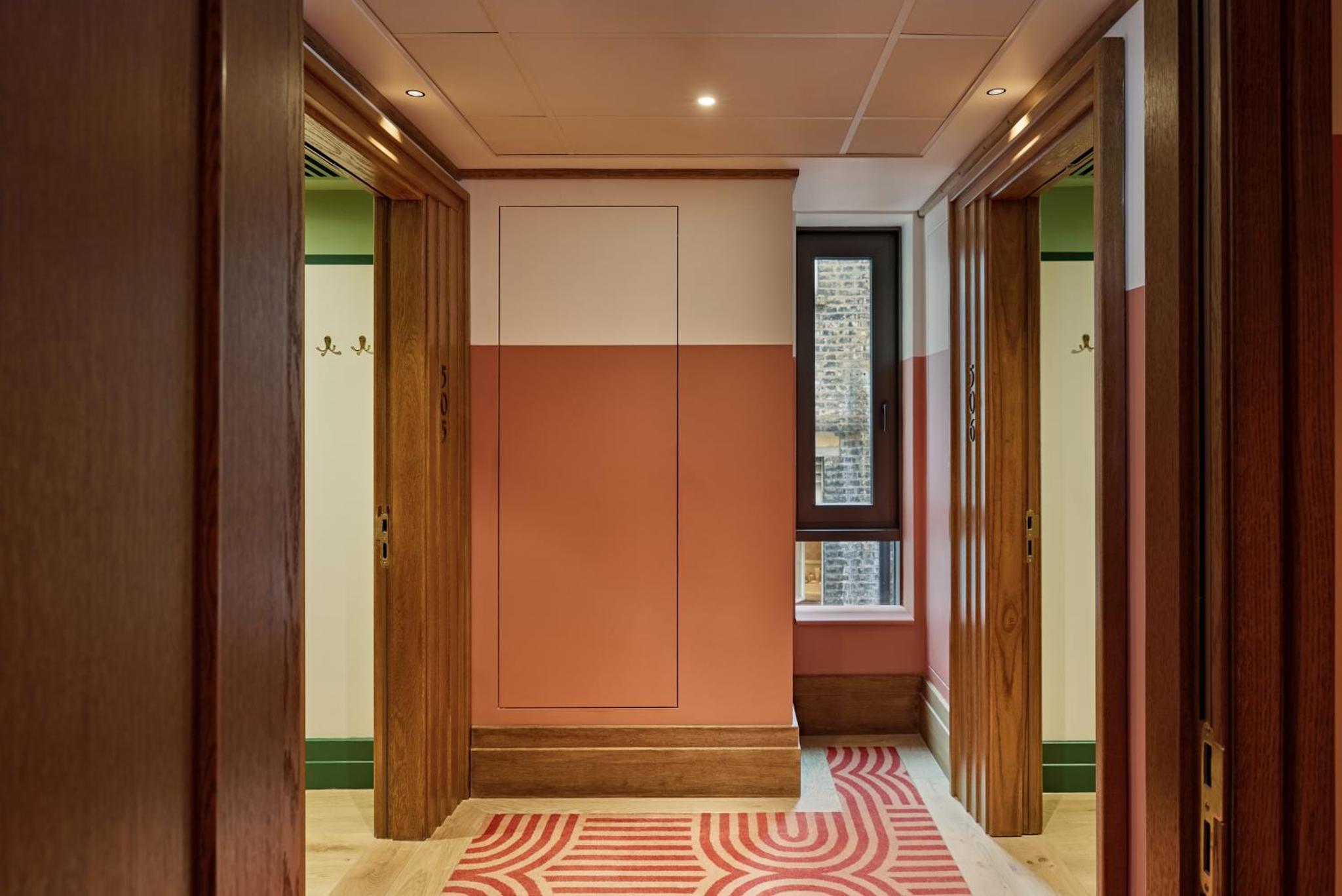 a hallway with doors and a red carpet at The July - London Victoria in London