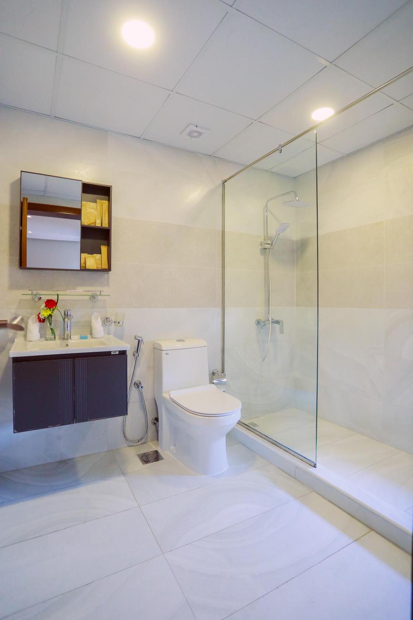 a bathroom with a toilet and a glass shower at SeaLoft Villas in Manama
