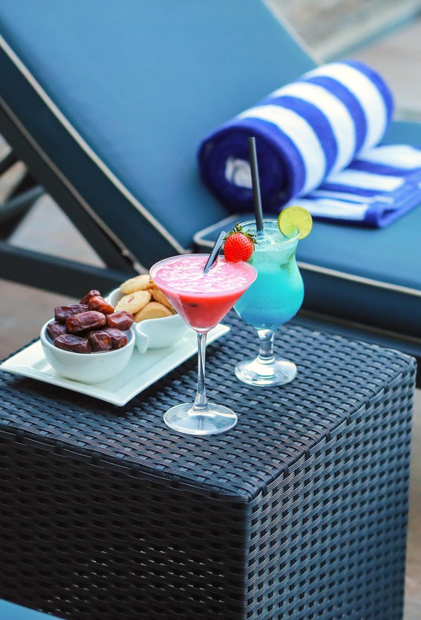 a table with two cocktails and a plate of food at SeaLoft Villas in Manama