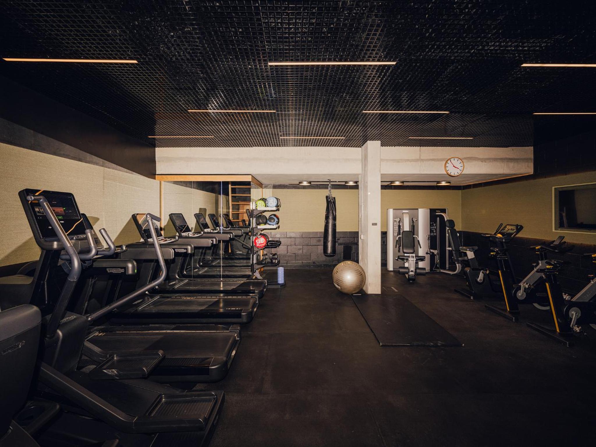 a gym with a row of treadmills and machines at Aethos Hotel London Shoreditch in London