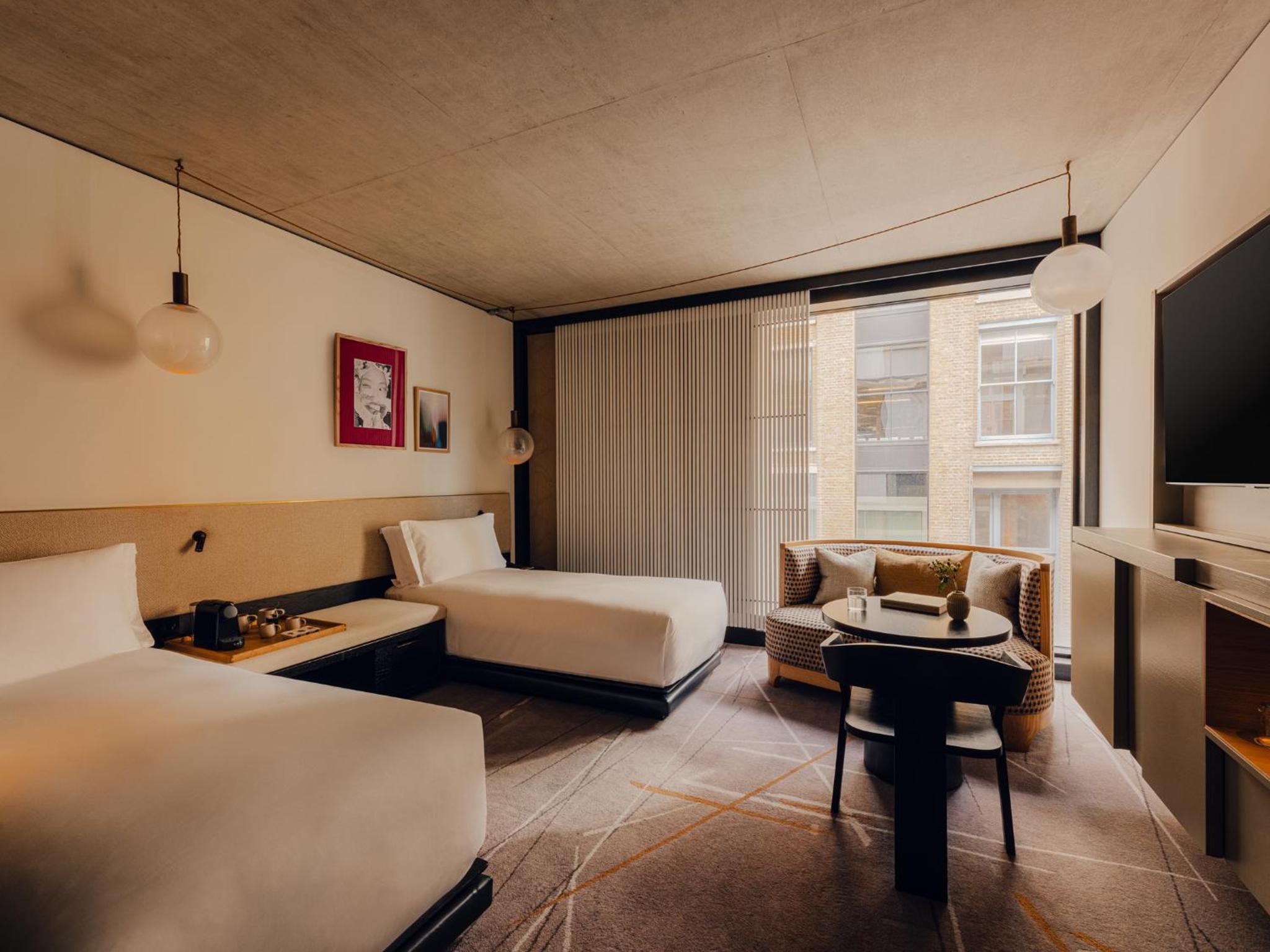 a hotel room with two beds and a chair at Aethos Hotel London Shoreditch in London