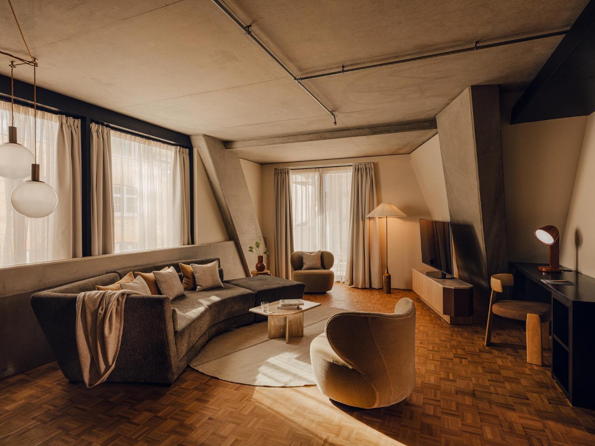 a living room with a couch and a chair at Aethos Hotel London Shoreditch in London