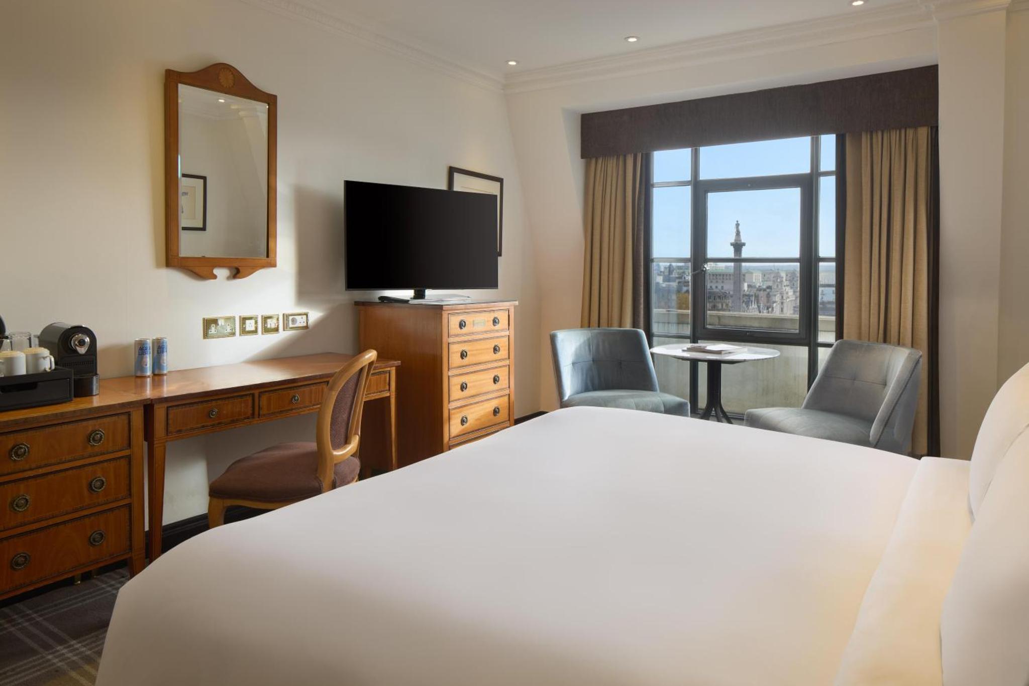 a hotel room with a bed and a desk and a television at Radisson Blu Hotel, London Leicester Square in London