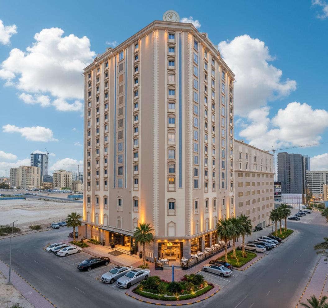 a large white building with cars parked in a parking lot at Ramee Rose Hotel in Manama