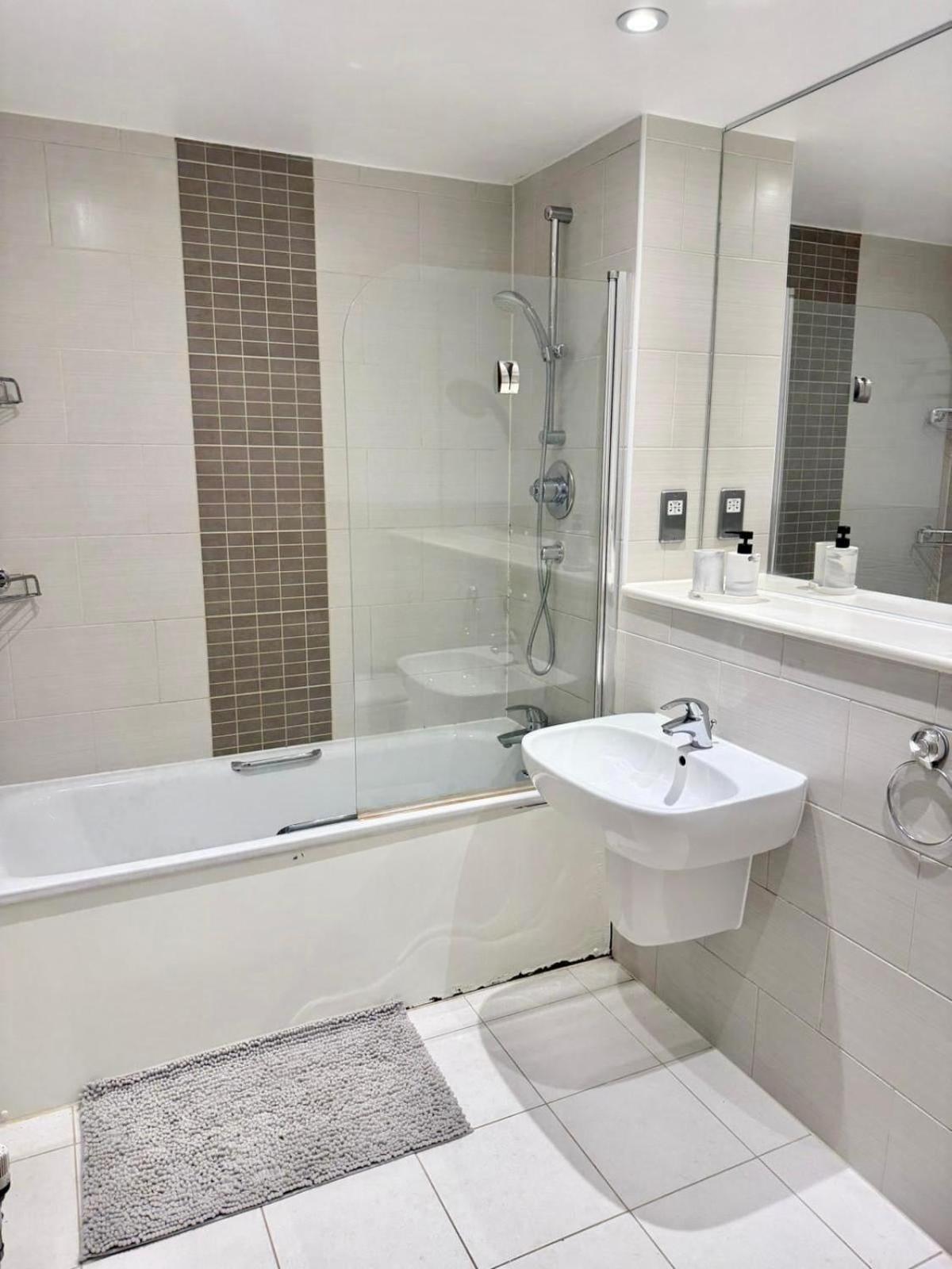 a bathroom with a sink and a tub and a shower at Spacious Flat Between Stockwell & Brixton in London