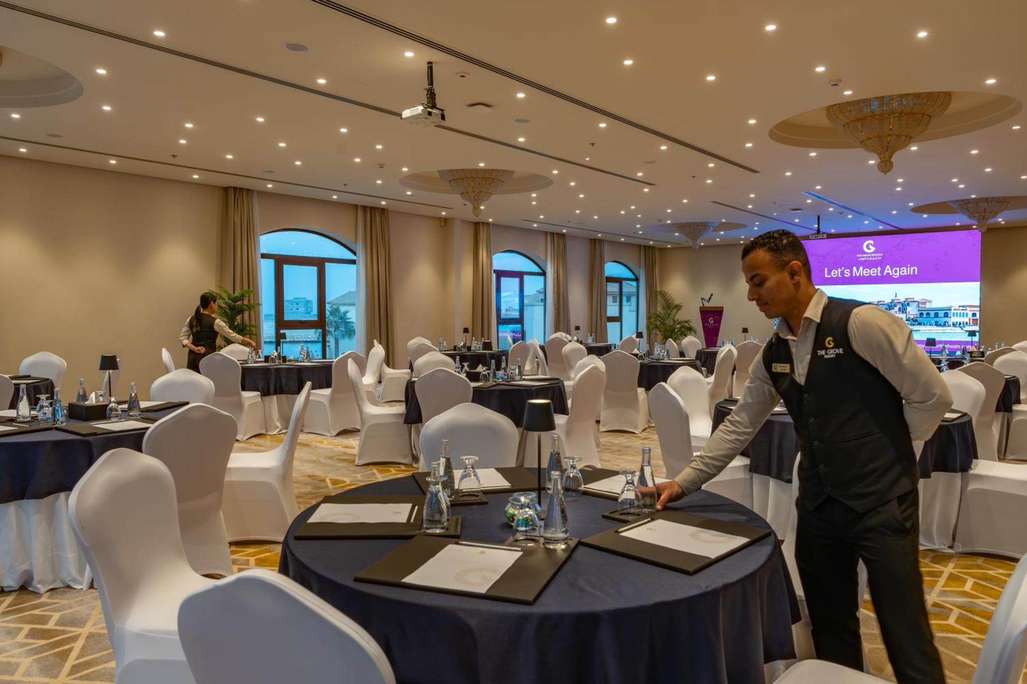 a man in a room with tables and chairs at The Grove Resort Bahrain in Manama