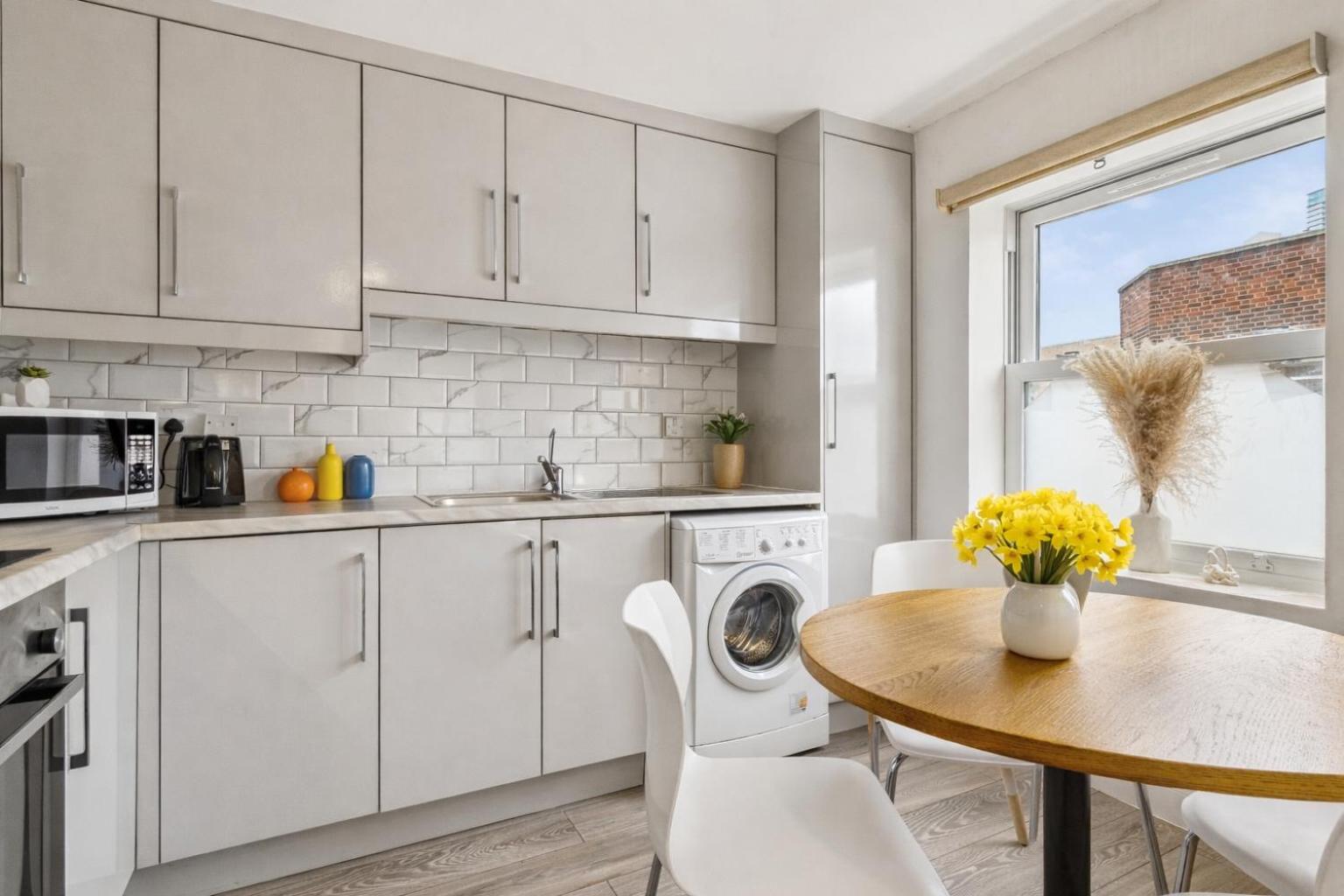 a kitchen with white cabinets and a table at Keyhol Short Stay I Trendy Flat I Bricklane Market in London +16 photos