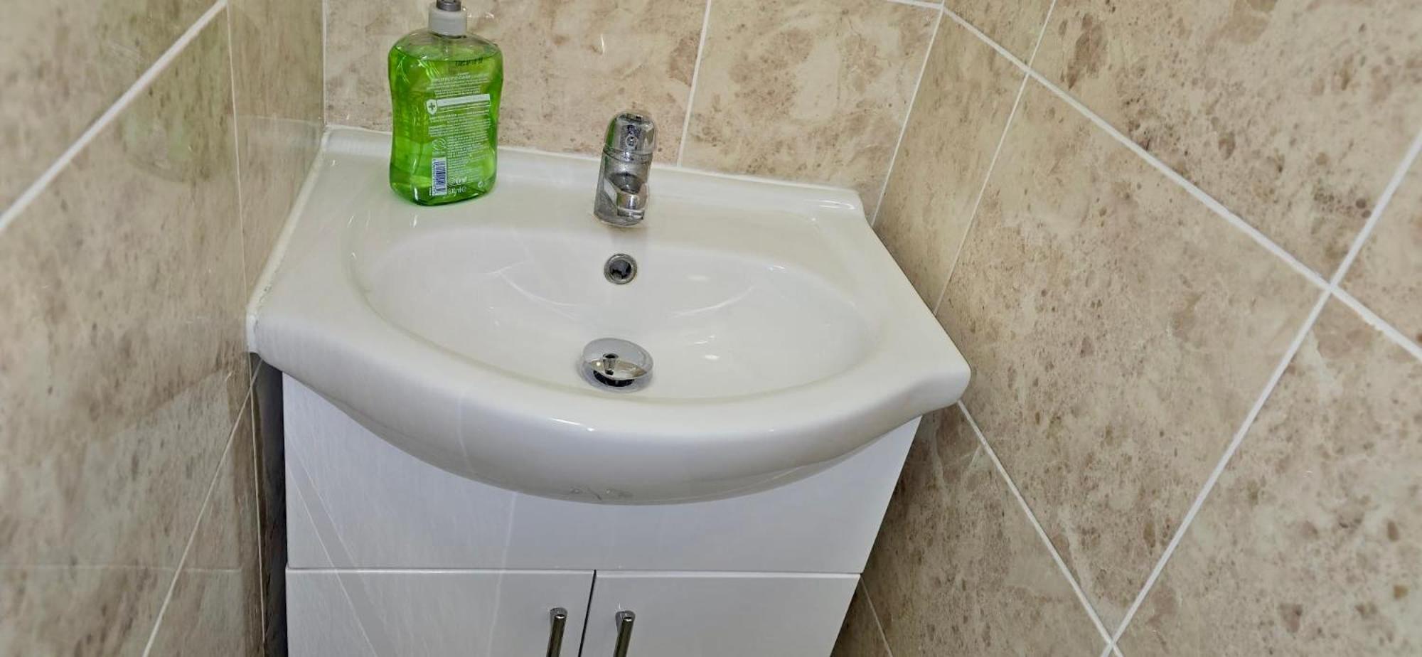 a bathroom sink with a green bottle on top of it at The Brick Lane Suites London in London
