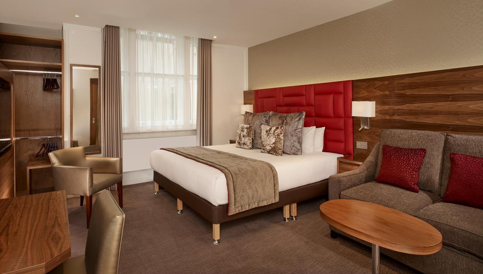 a hotel room with a bed and a couch at Norfolk Towers Paddington in London