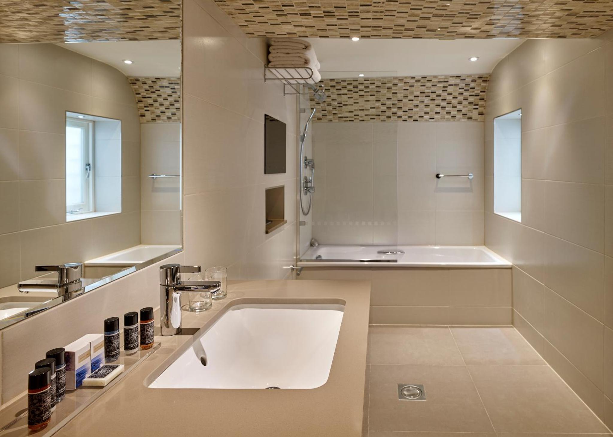a bathroom with a large white sink and a tub at Norfolk Towers Paddington in London