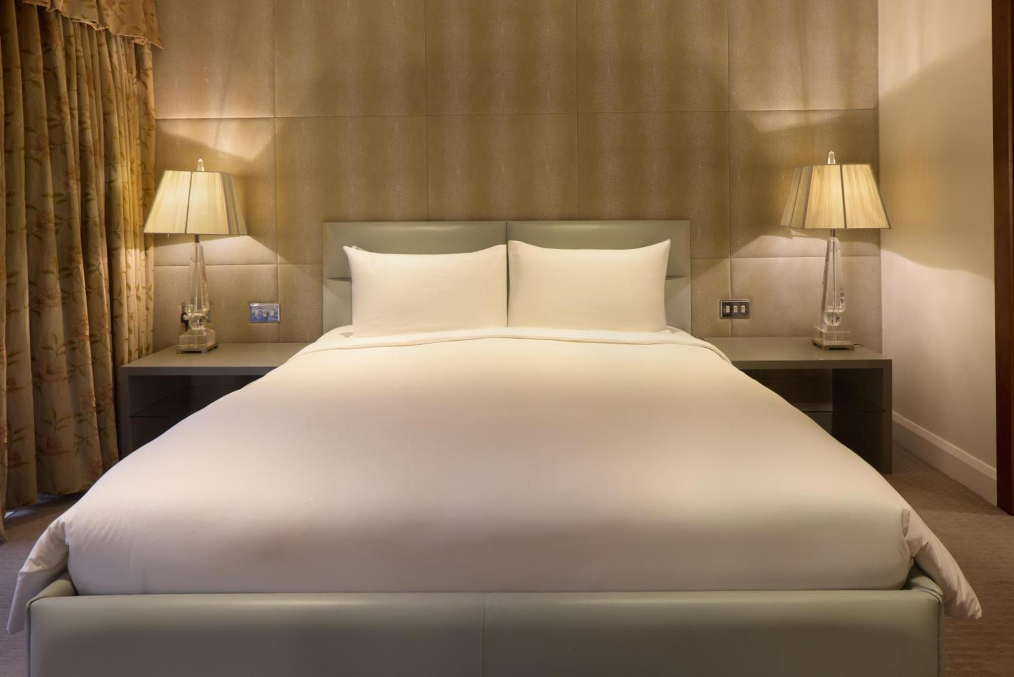 a large white bed in a hotel room with two lamps at Radisson Blu Hotel, London Leicester Square in London