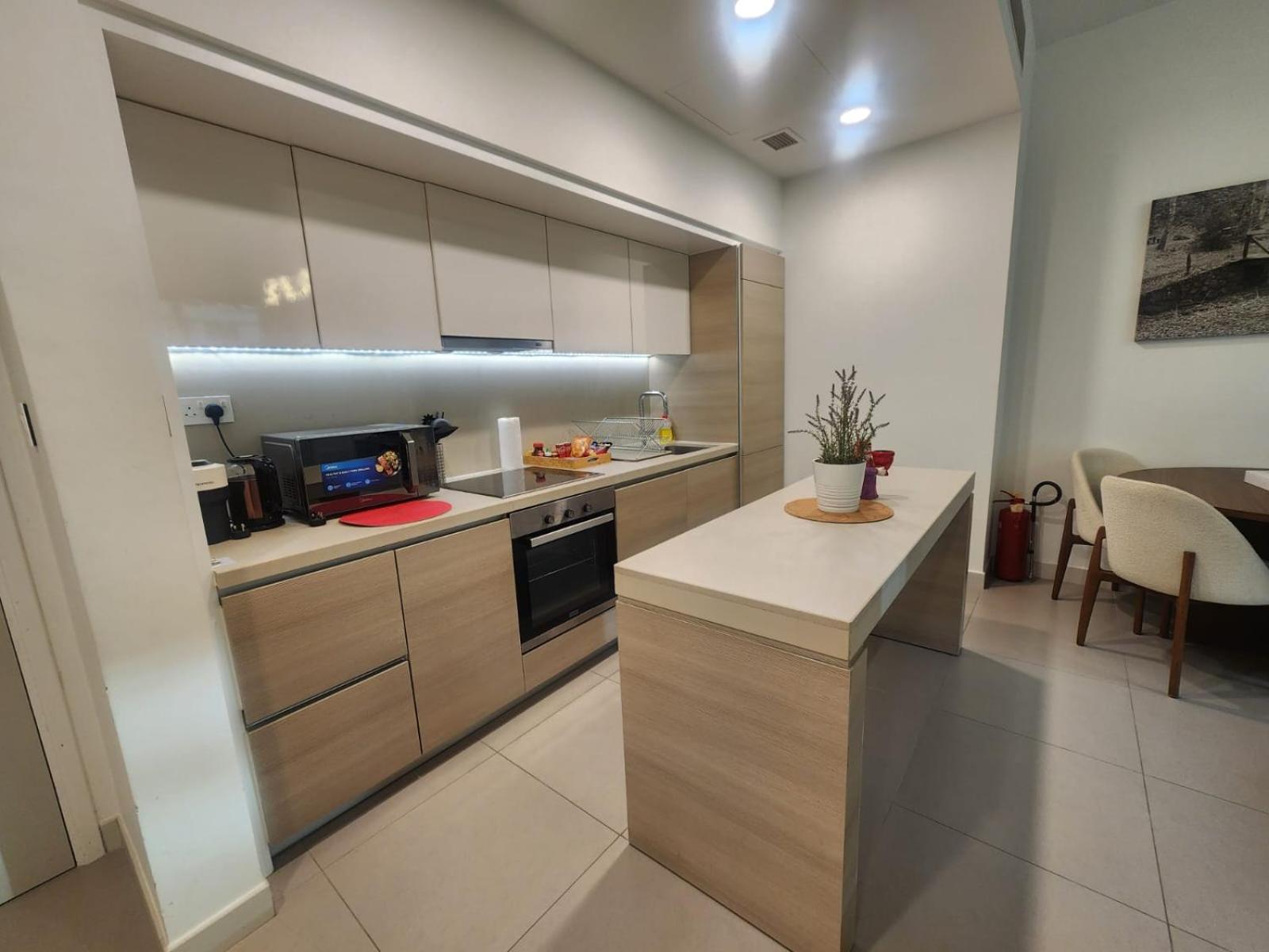 a kitchen with a counter and a table in it at Luxury 2BR with Private Garden Marassi Living in Rayyā