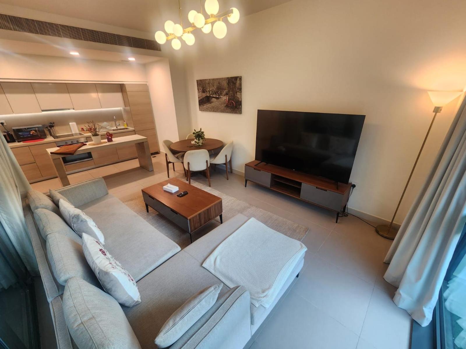a living room with a couch and a flat screen tv at Luxury 2BR with Private Garden Marassi Living in Rayyā