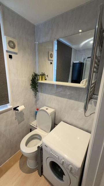 a small bathroom with a toilet and a washing machine at Cosy central studio close to local attractions in London