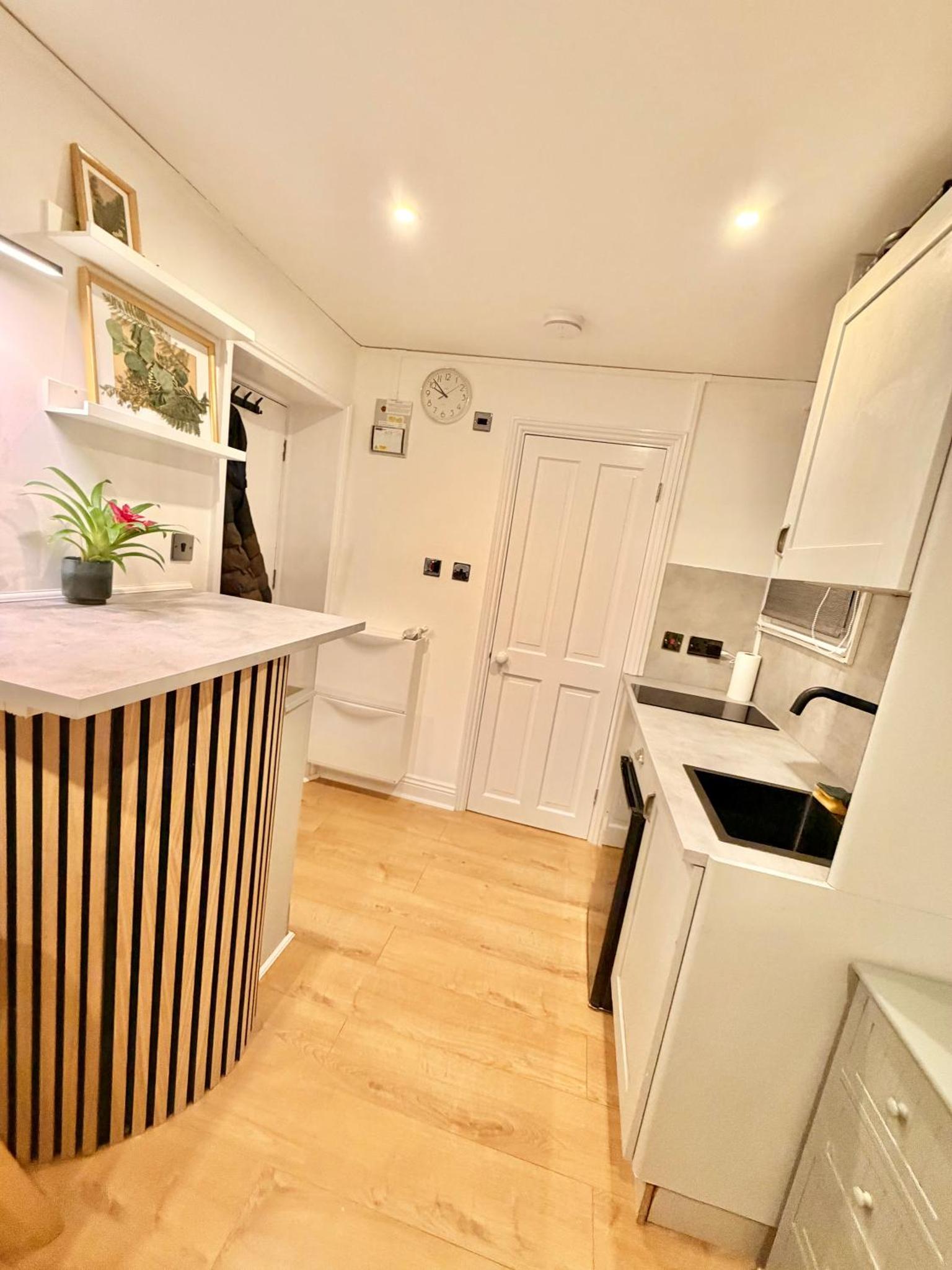 a kitchen with white appliances and a wooden floor at Cosy central studio close to local attractions in London