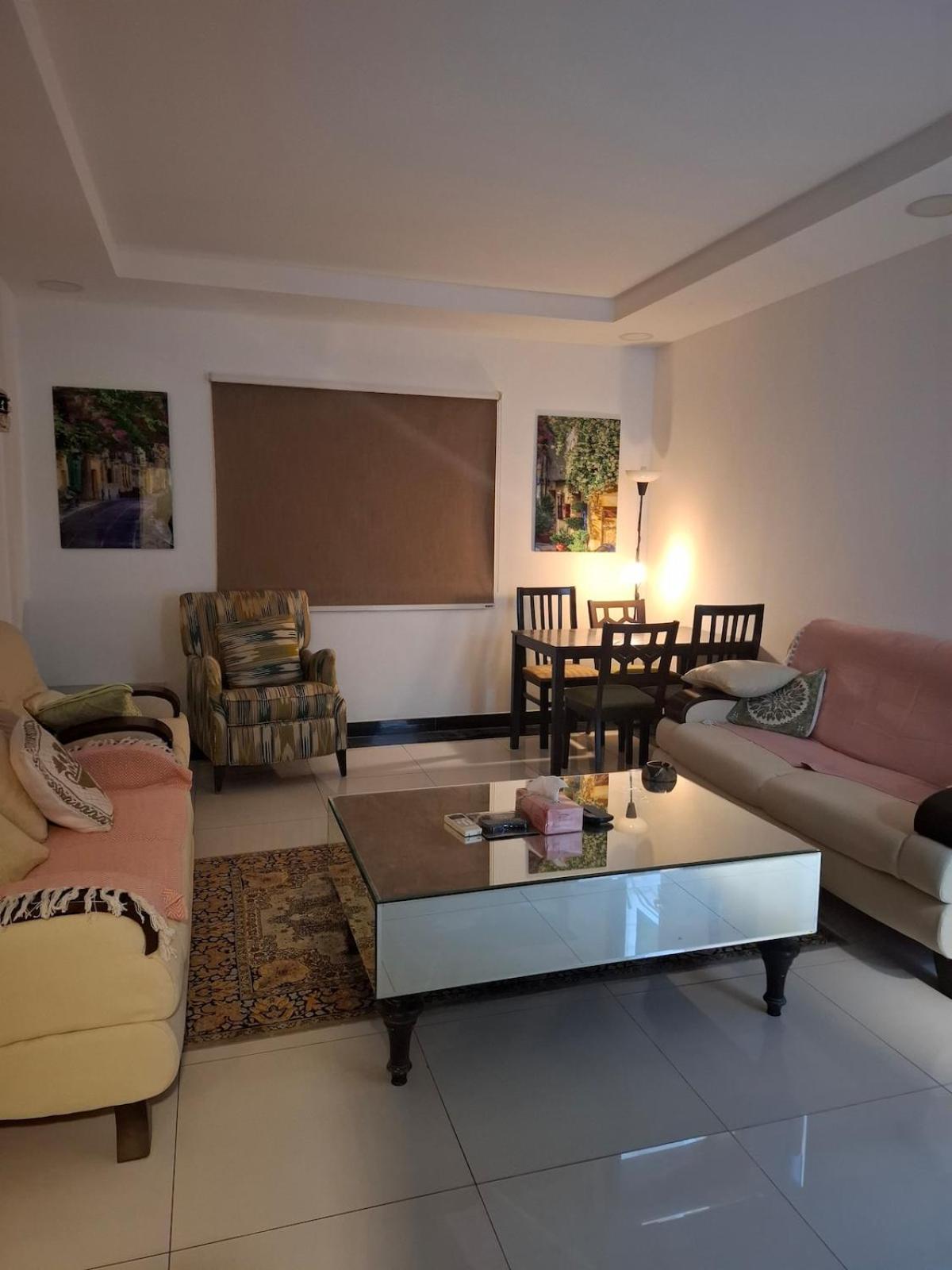 a living room with couches and a table and a screen at Cozy rustic el carro Apartment in Umm ash Shajar