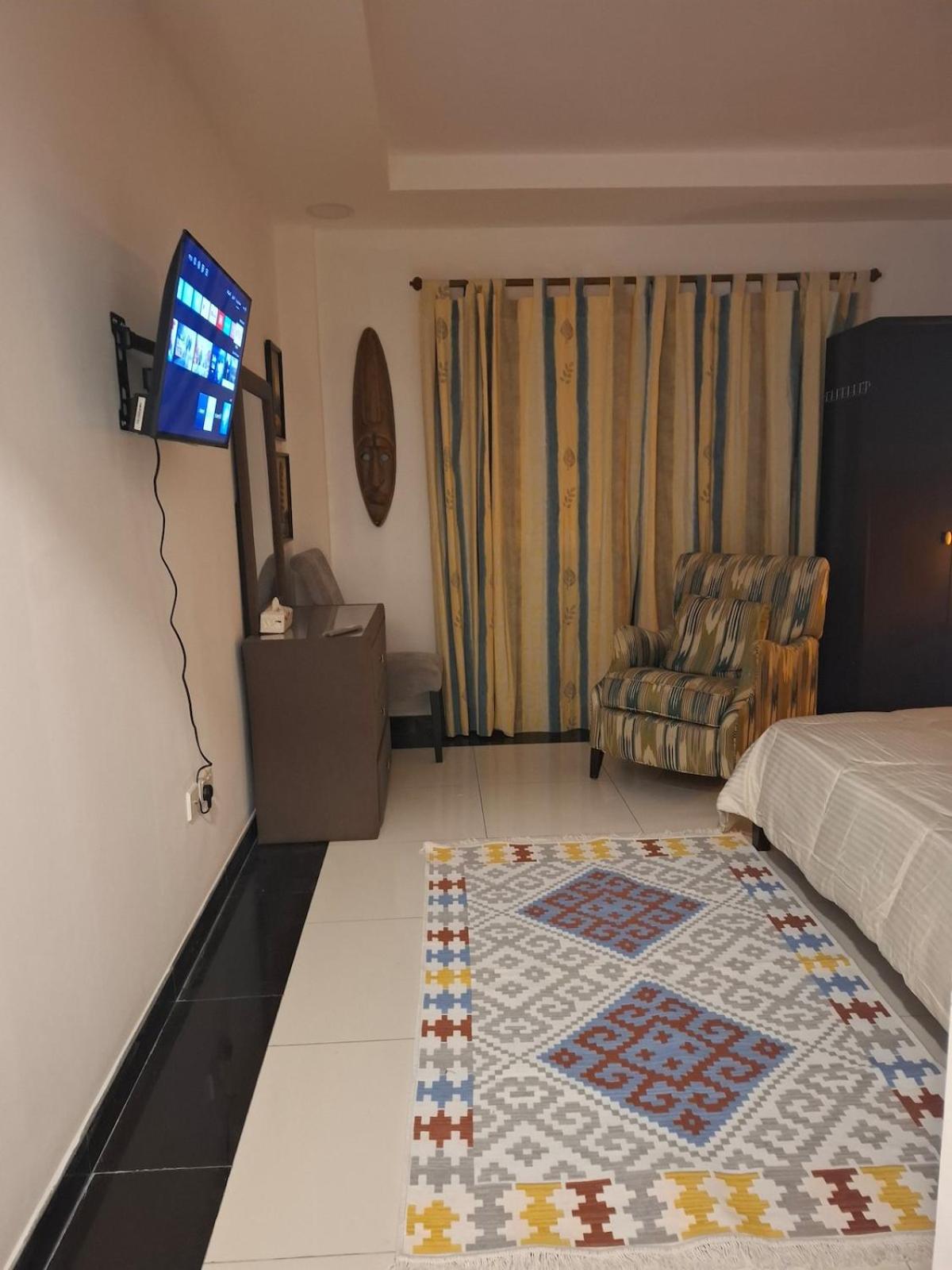 a bedroom with a bed and a television and a rug at Cozy rustic el carro Apartment in Umm ash Shajar