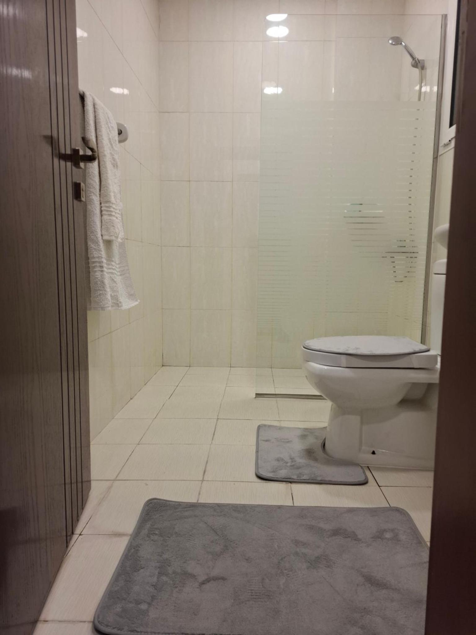 a bathroom with a toilet and a glass shower at Cozy rustic el carro Apartment in Umm ash Shajar +3 photos