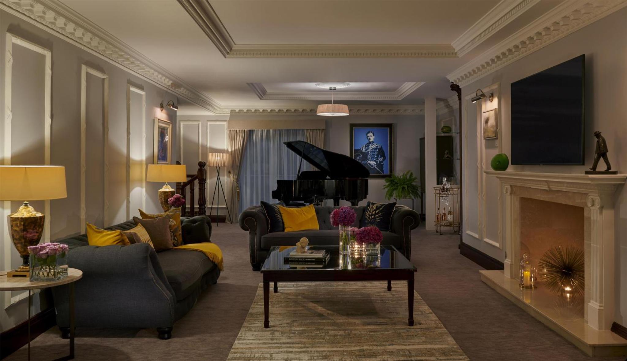 a living room with a couch and a piano at Hyatt Regency London - The Churchill in London