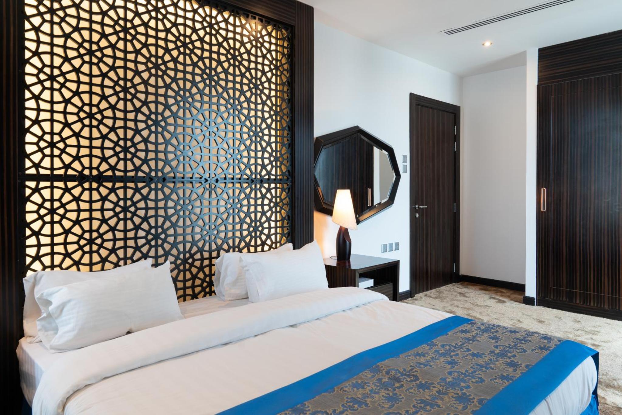 a bedroom with a large bed and a mirror at Seef Residence in Seef