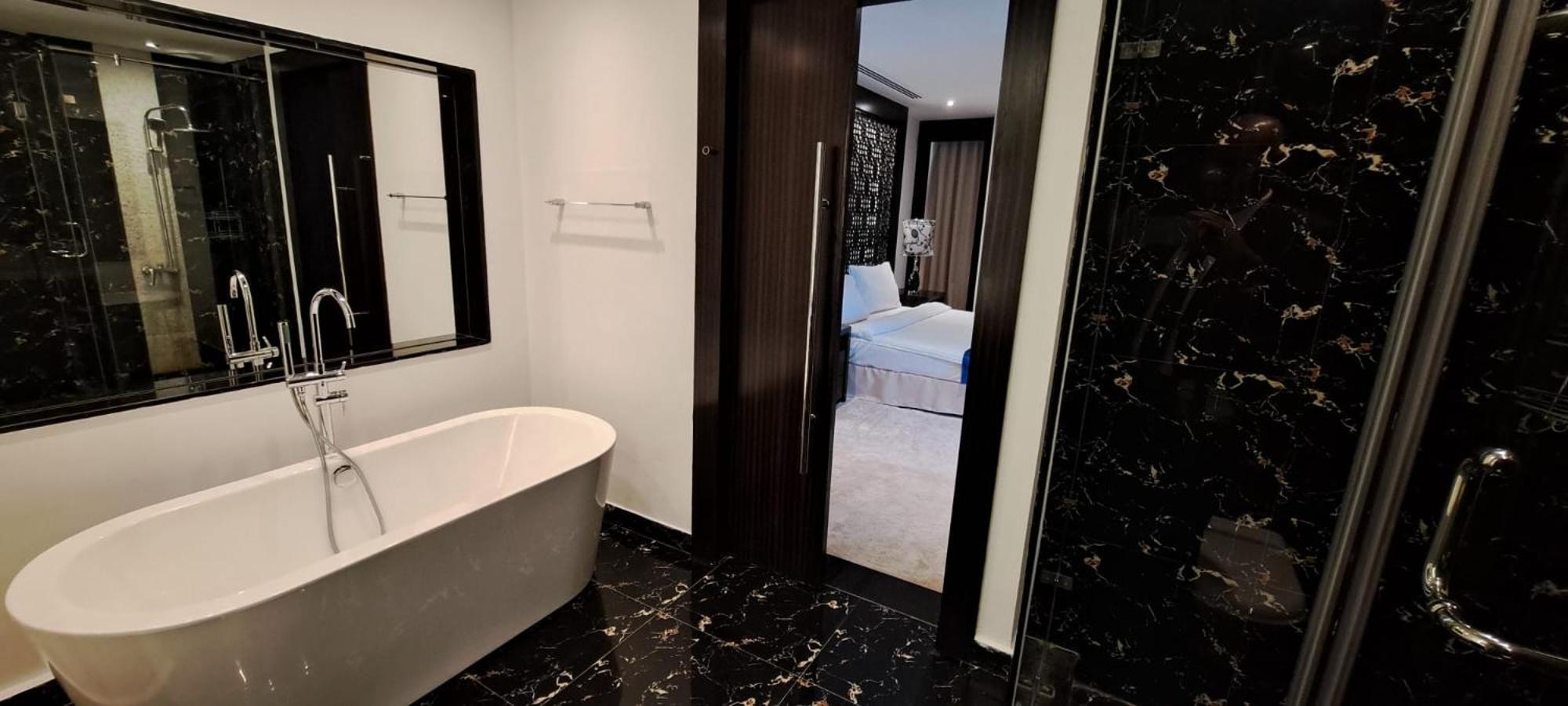 a bathroom with a bath tub and a shower at Seef Residence in Seef