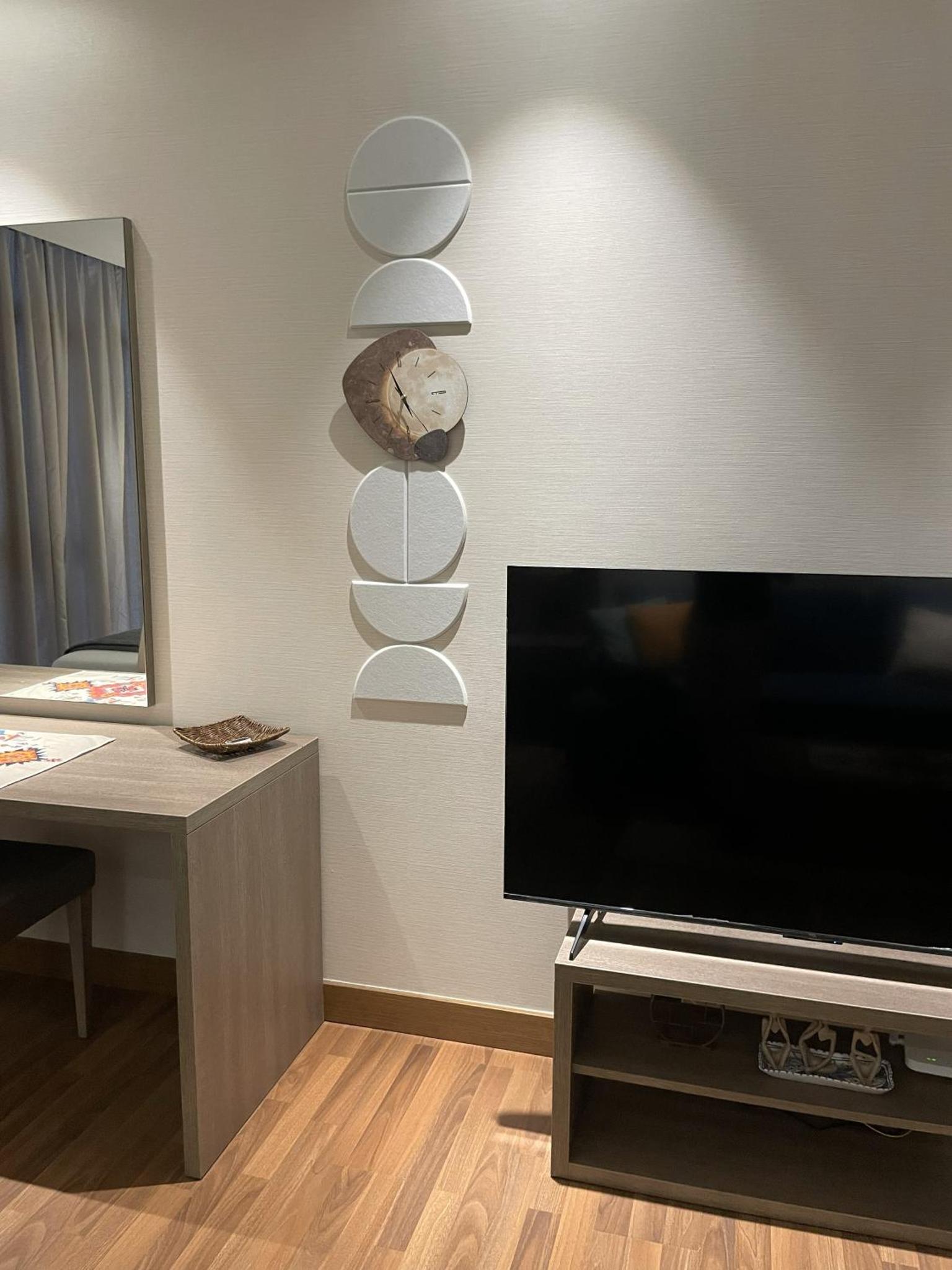 a living room with a tv and a clock on the wall at Boho Cozy Escape in Quiet Neighborhood in Sanābis +5 photos