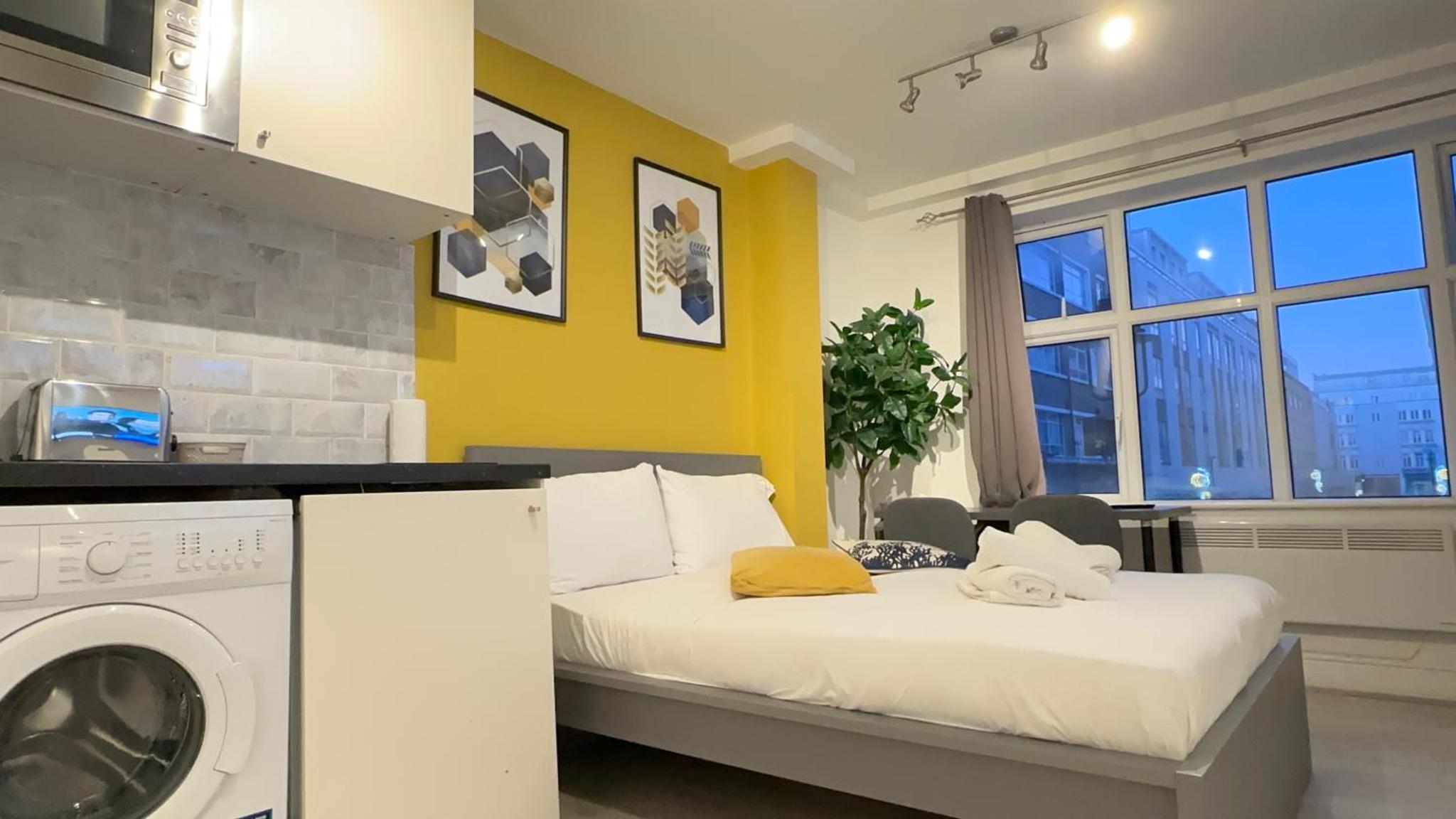 a bedroom with a bed and a washing machine at Cosy Farringdon Apartments in London