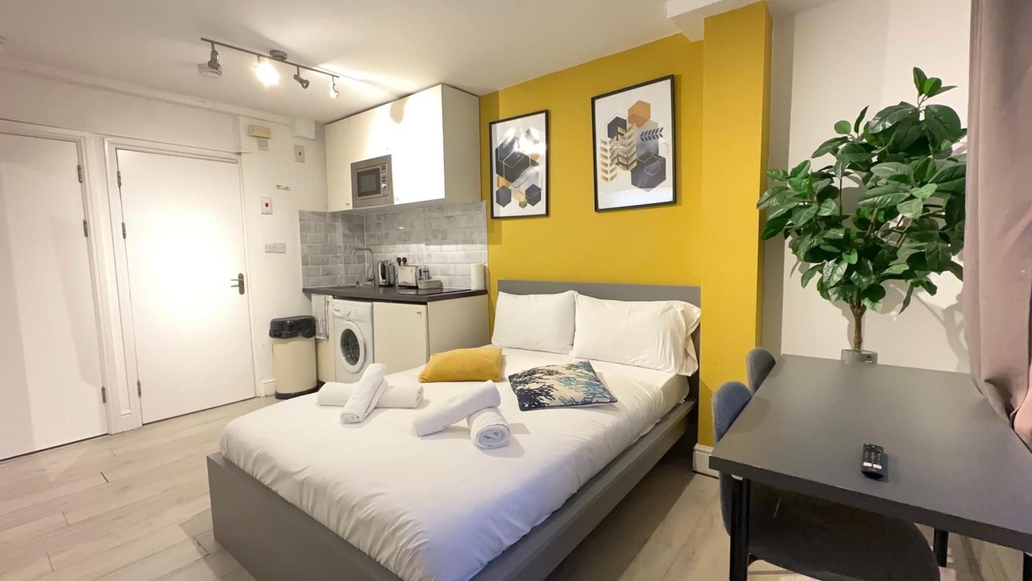 a bedroom with a bed and a small kitchen at Cosy Farringdon Apartments in London
