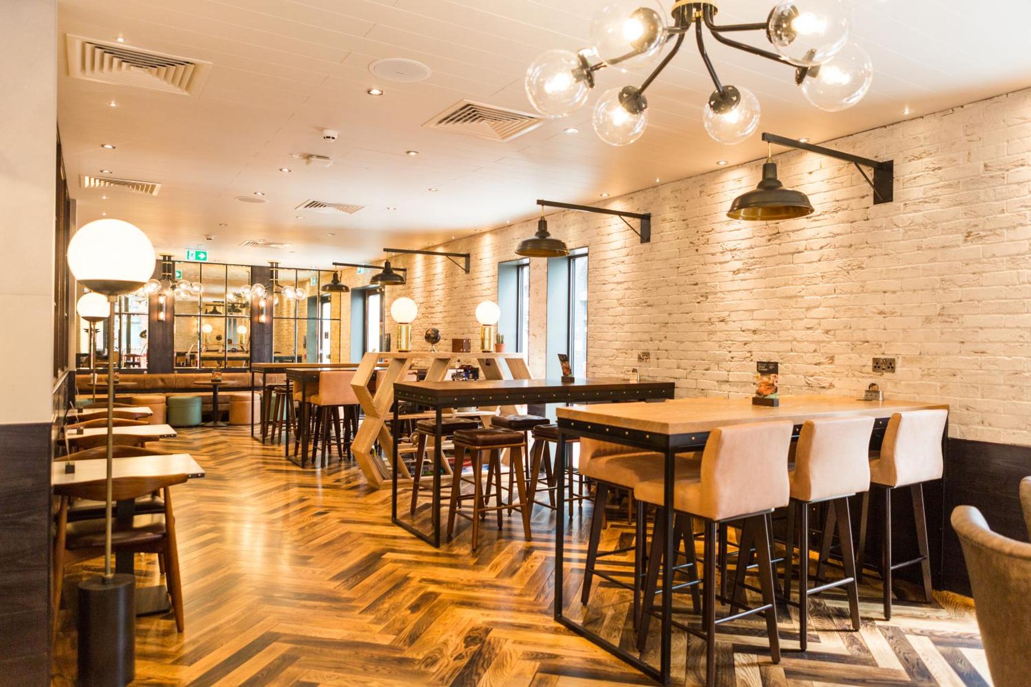 a restaurant with wooden floors and tables and chairs at hub London - King's Cross in London +21 photos