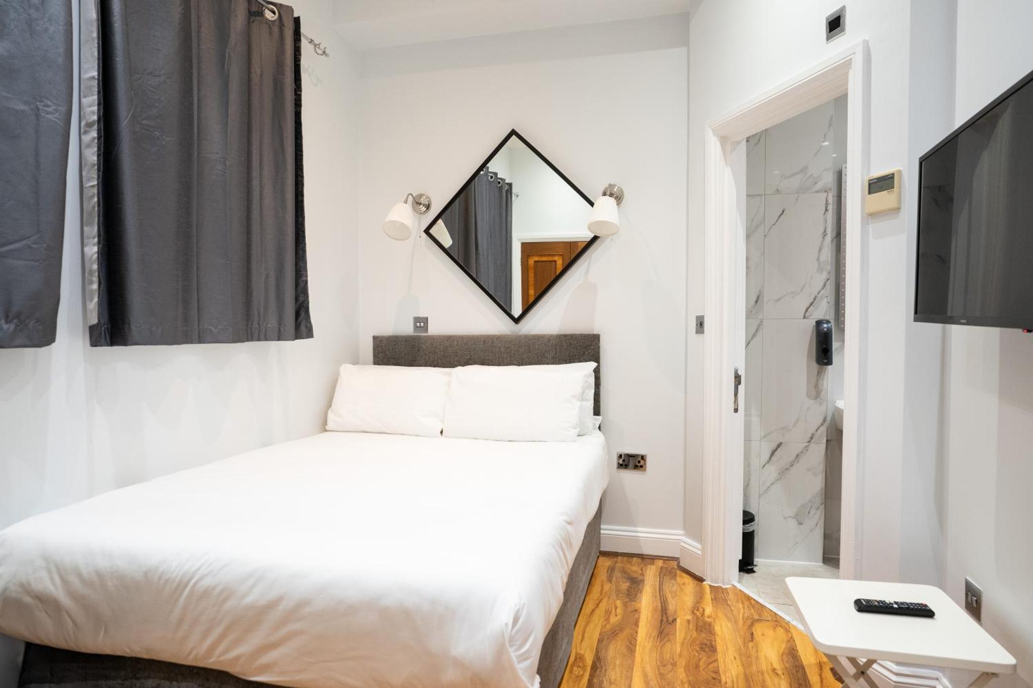 a bedroom with a white bed and a mirror at MSK Hotel 82 in London