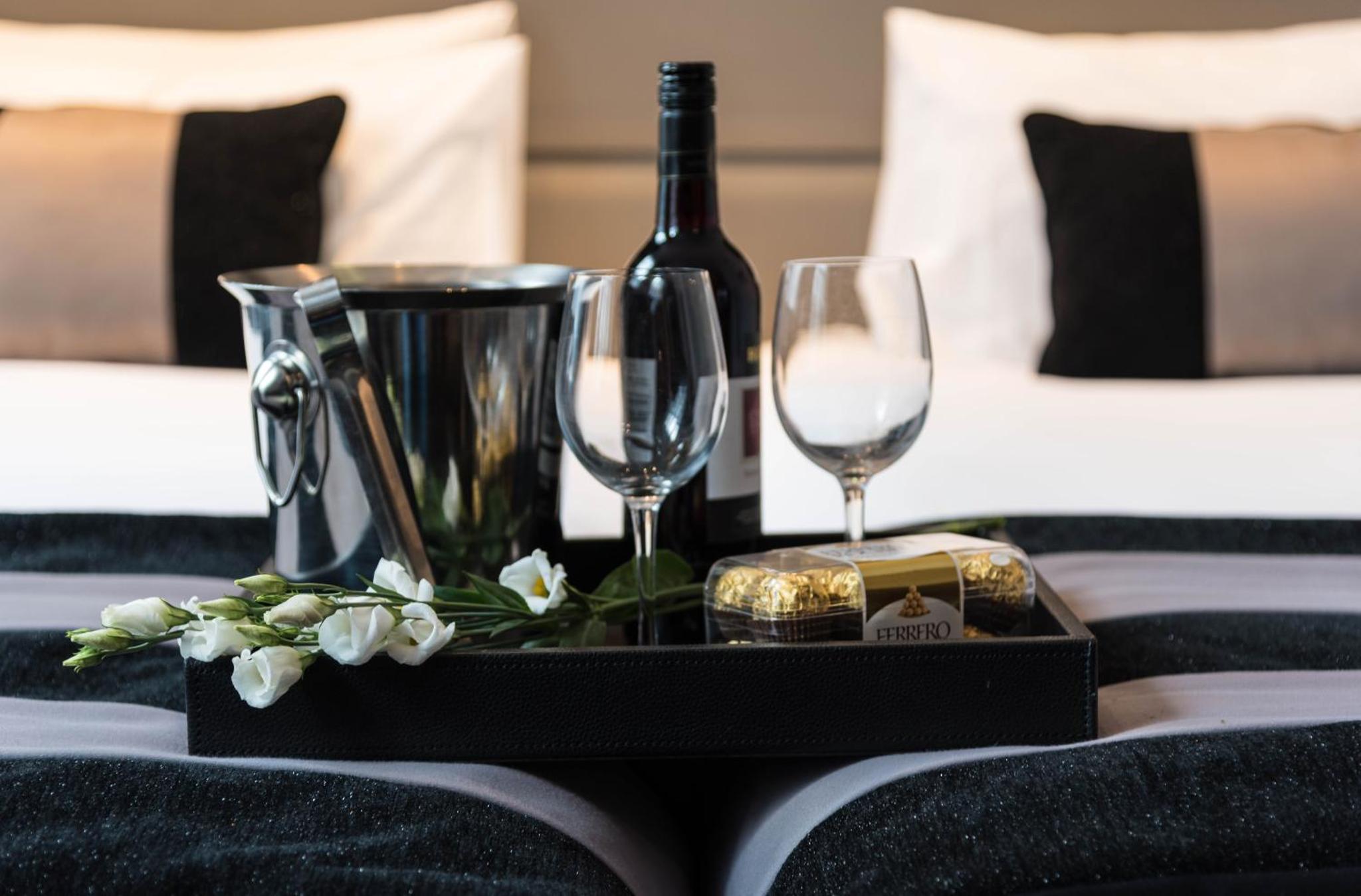 a tray with a bottle of wine and glasses on a bed at Park Avenue Baker Street in London +23 photos