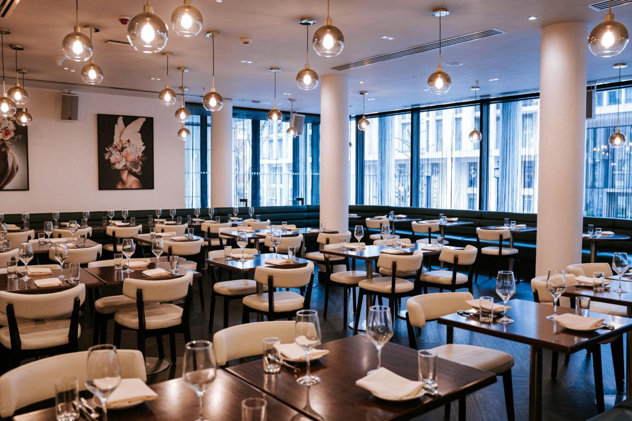 a dining room with tables and chairs and windows at Riu Plaza London The Westminster in London