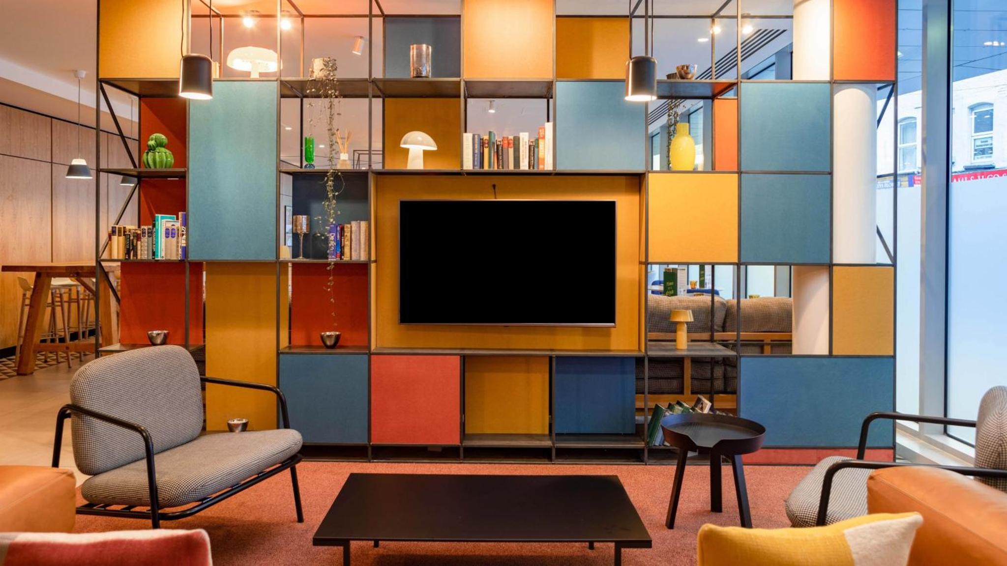 a living room with a tv and a colorful wall at Holiday Inn London - Whitechapel by IHG in London