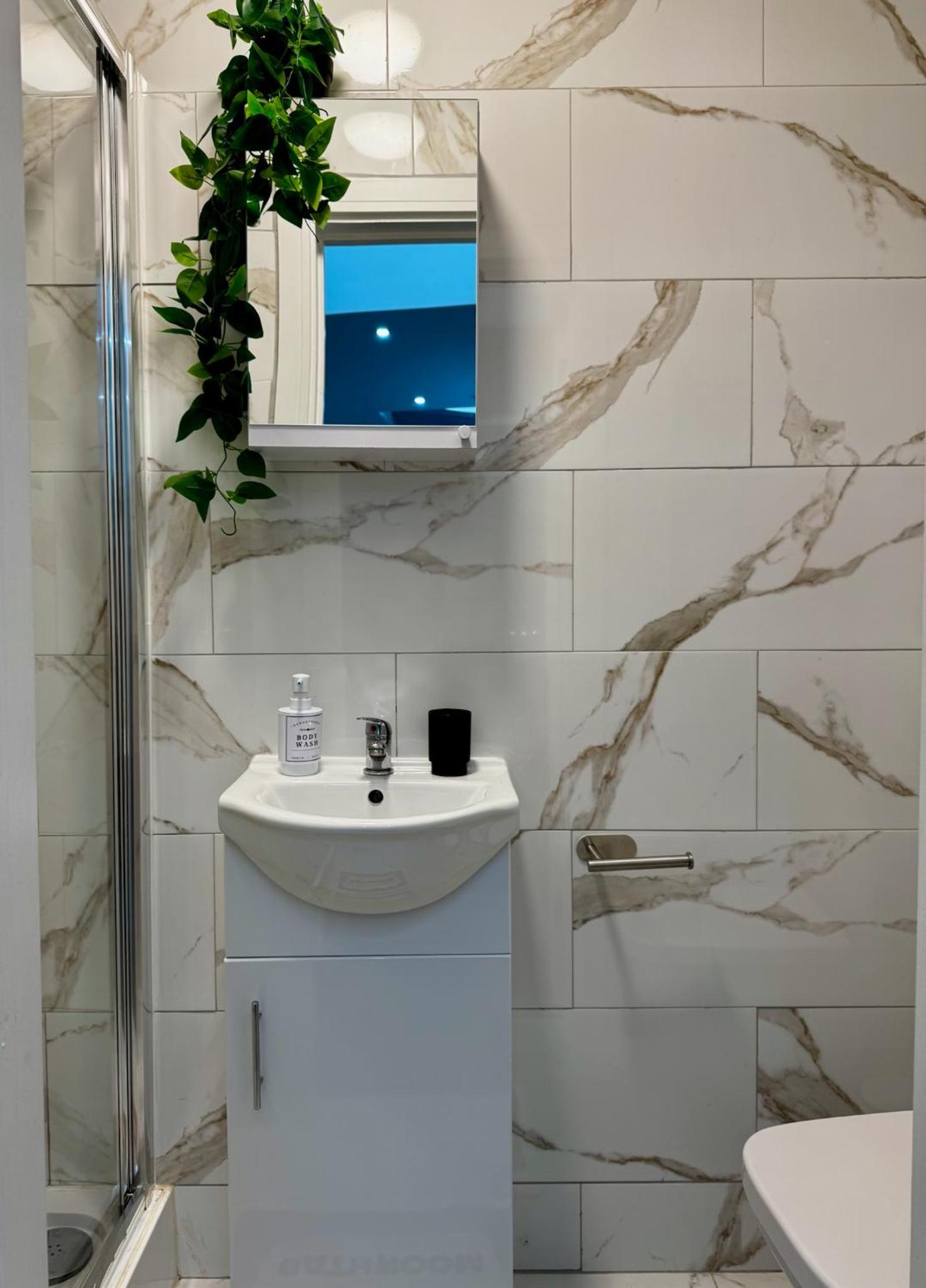 a white bathroom with a sink and a mirror at Tambo Apartments, 6 Apartments, Sleeps up to 26, only 25 Min to Central London in London +190 photos