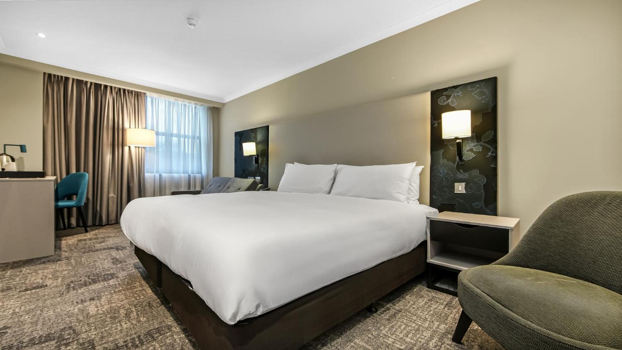 a hotel room with a large bed and a chair at Doubletree By Hilton London Kensington in London +37 photos