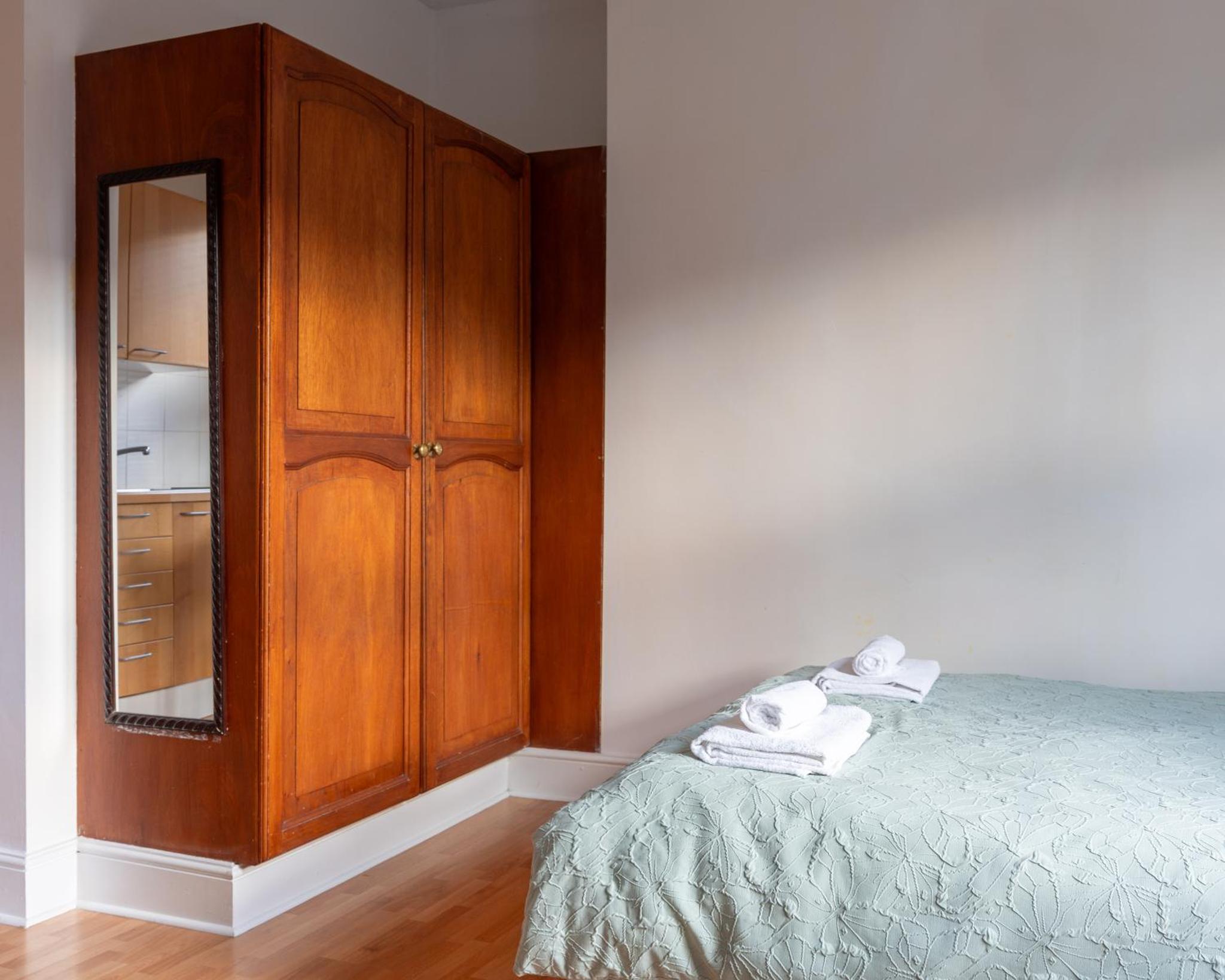 a bedroom with a cabinet and a bed with towels at Studio apartment next to Highgate tube station in London