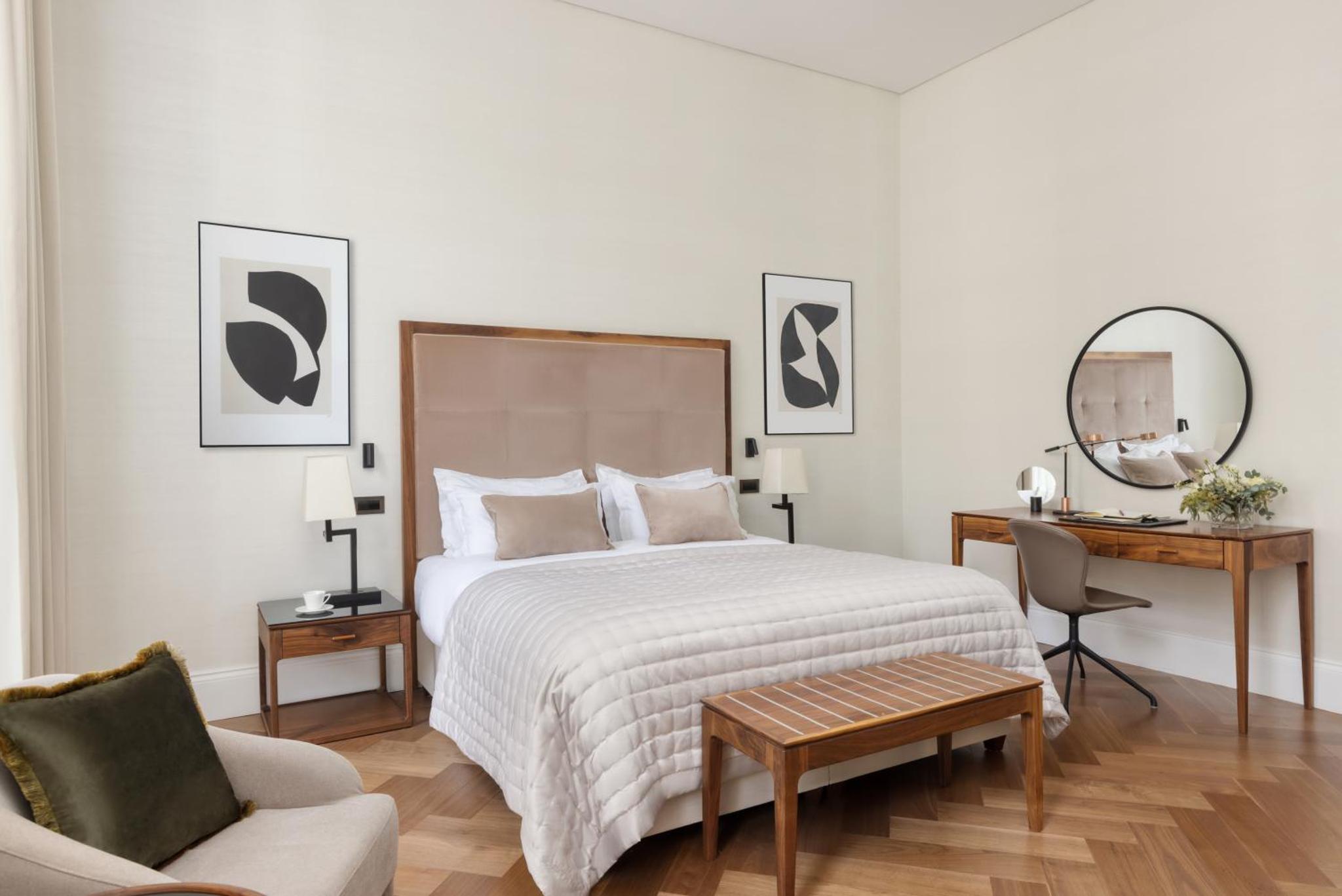 a bedroom with a bed and a chair and a mirror at The Queens Gate Hotel in London